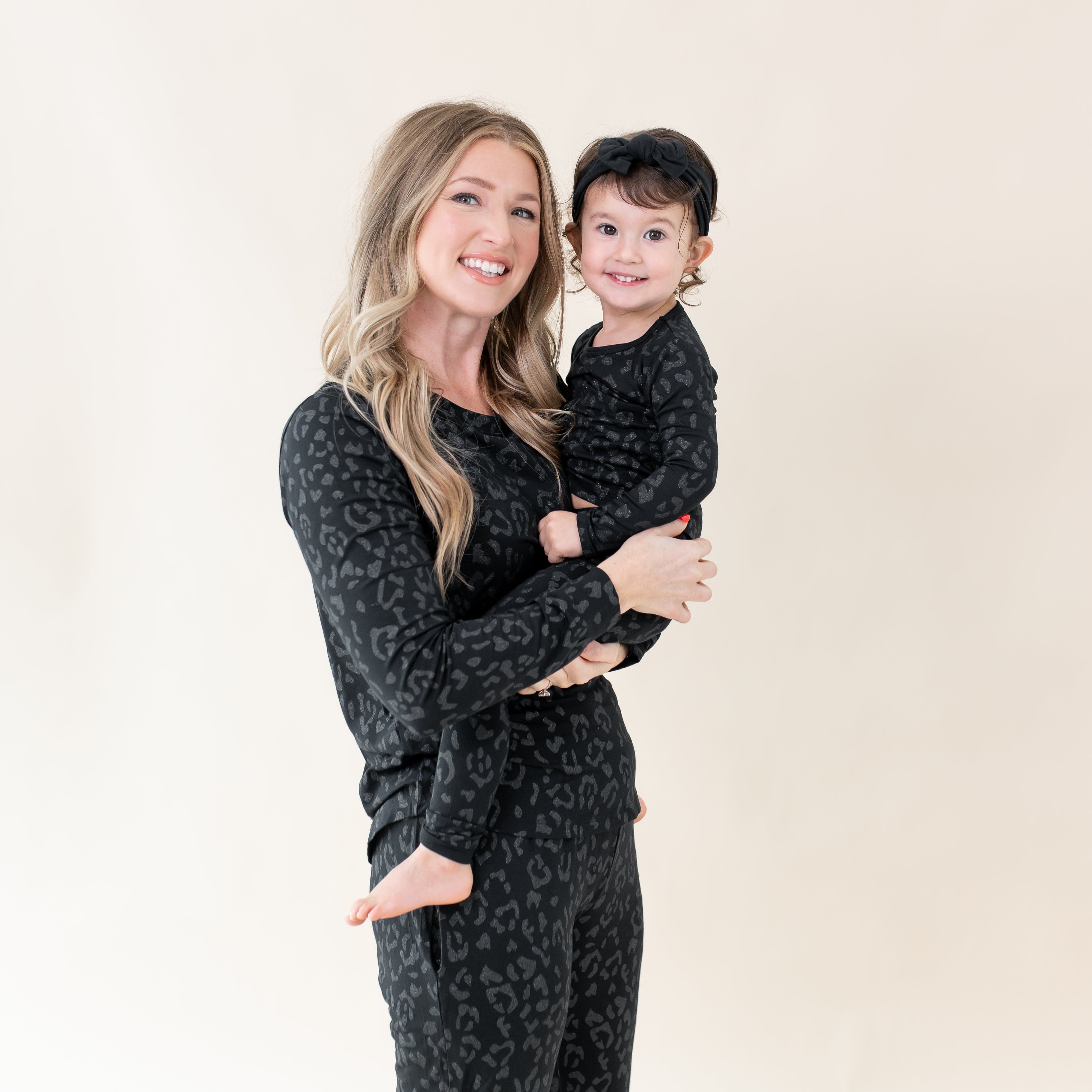 Mom and Toddler wearing matching two piece Kyte Baby Long Sleeve Pajamas in Midnight Leopard
