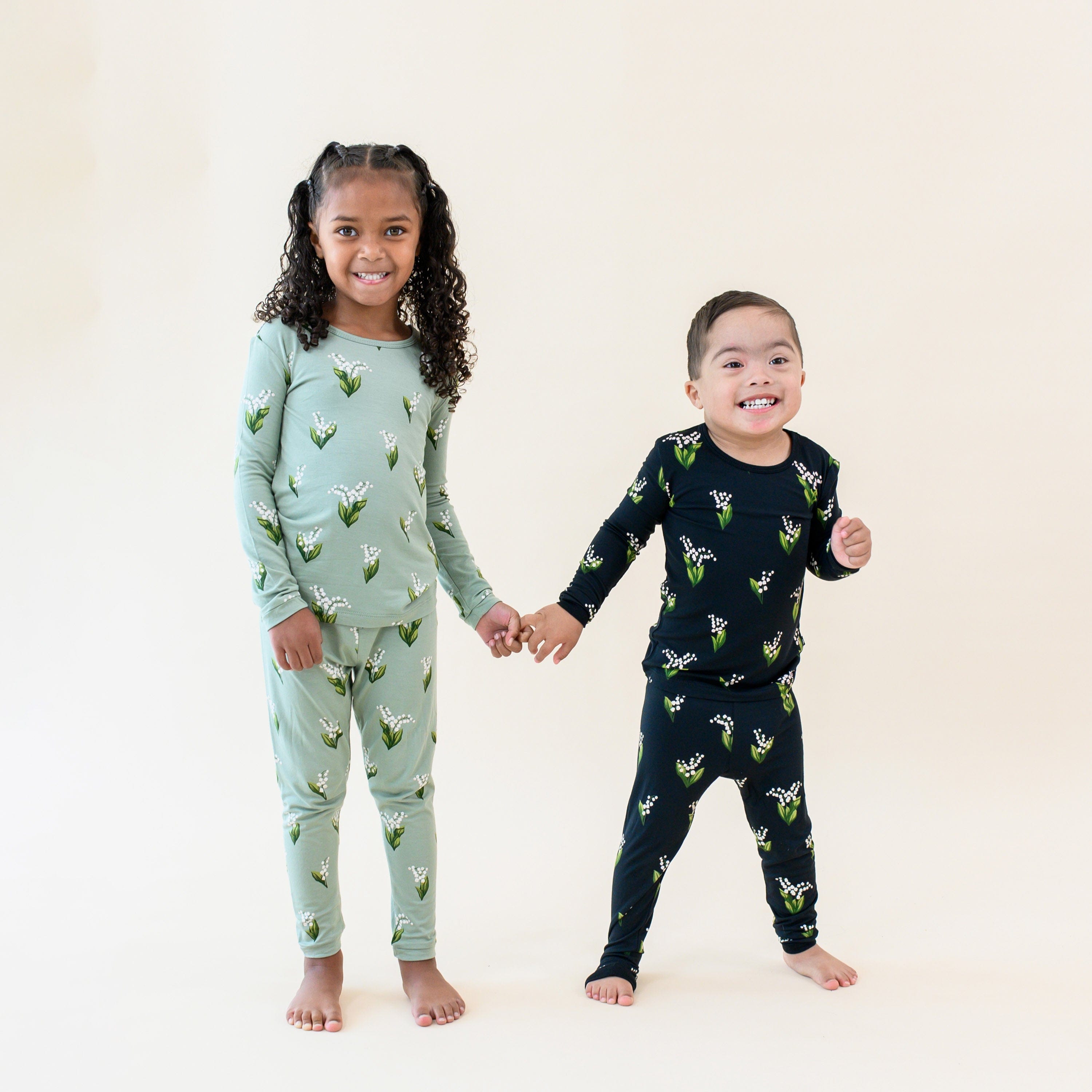 Kids wearing Kyte Baby long sleeve pajamas in Lily pattern