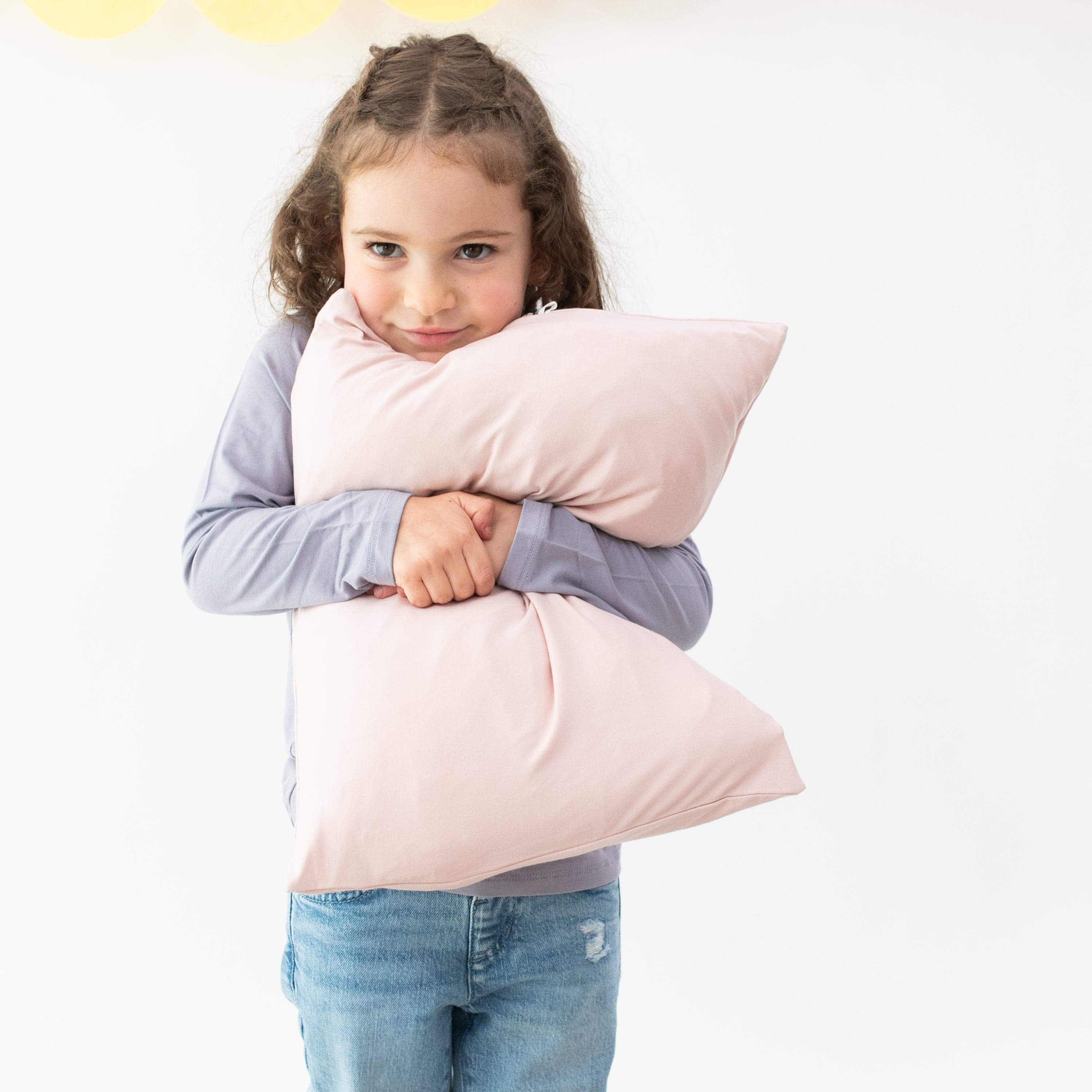 Girl holding Kyte Baby Toddler Pillowcase in Blush