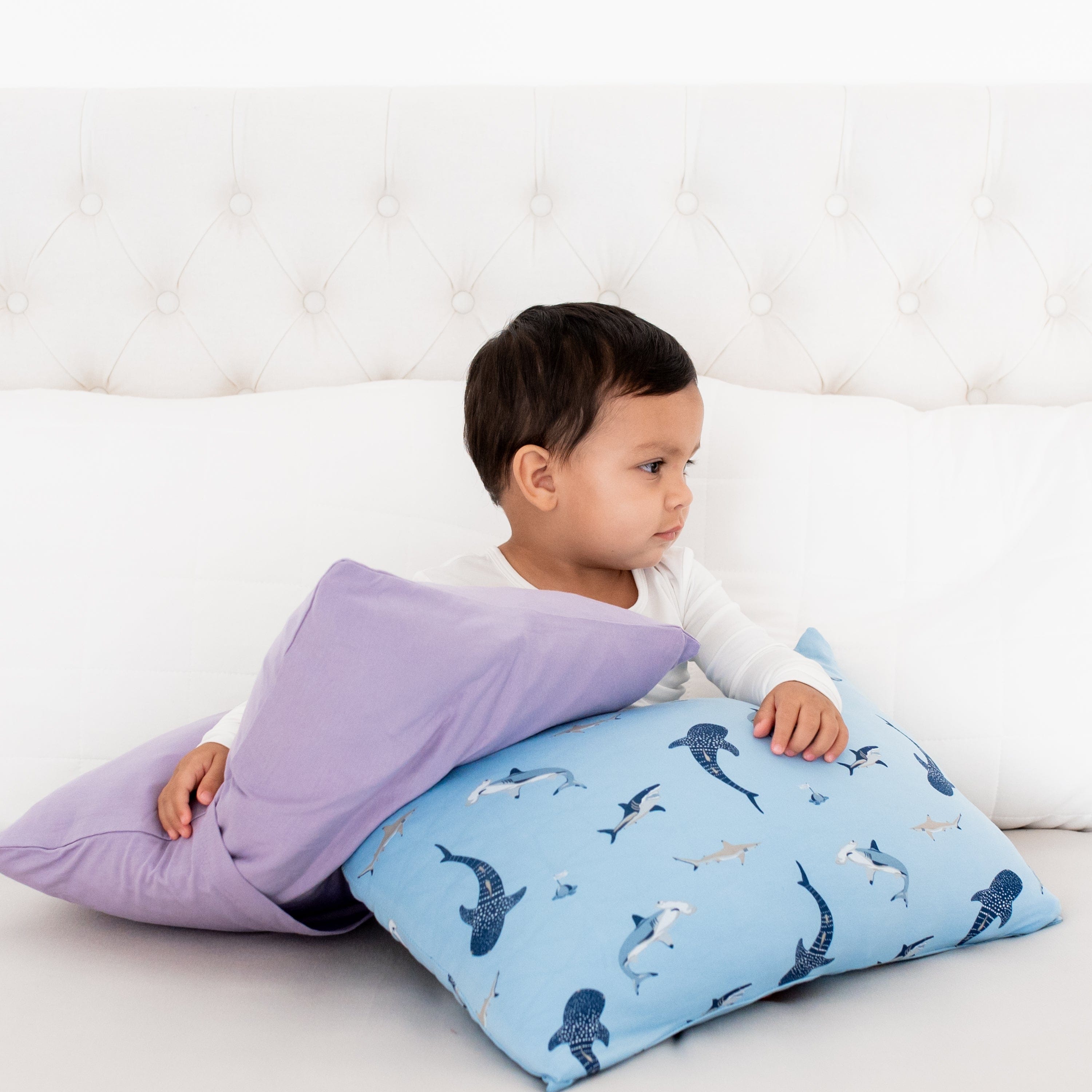 Toddler holding Kyte Baby Pillowcase in Taro and Stream Shark