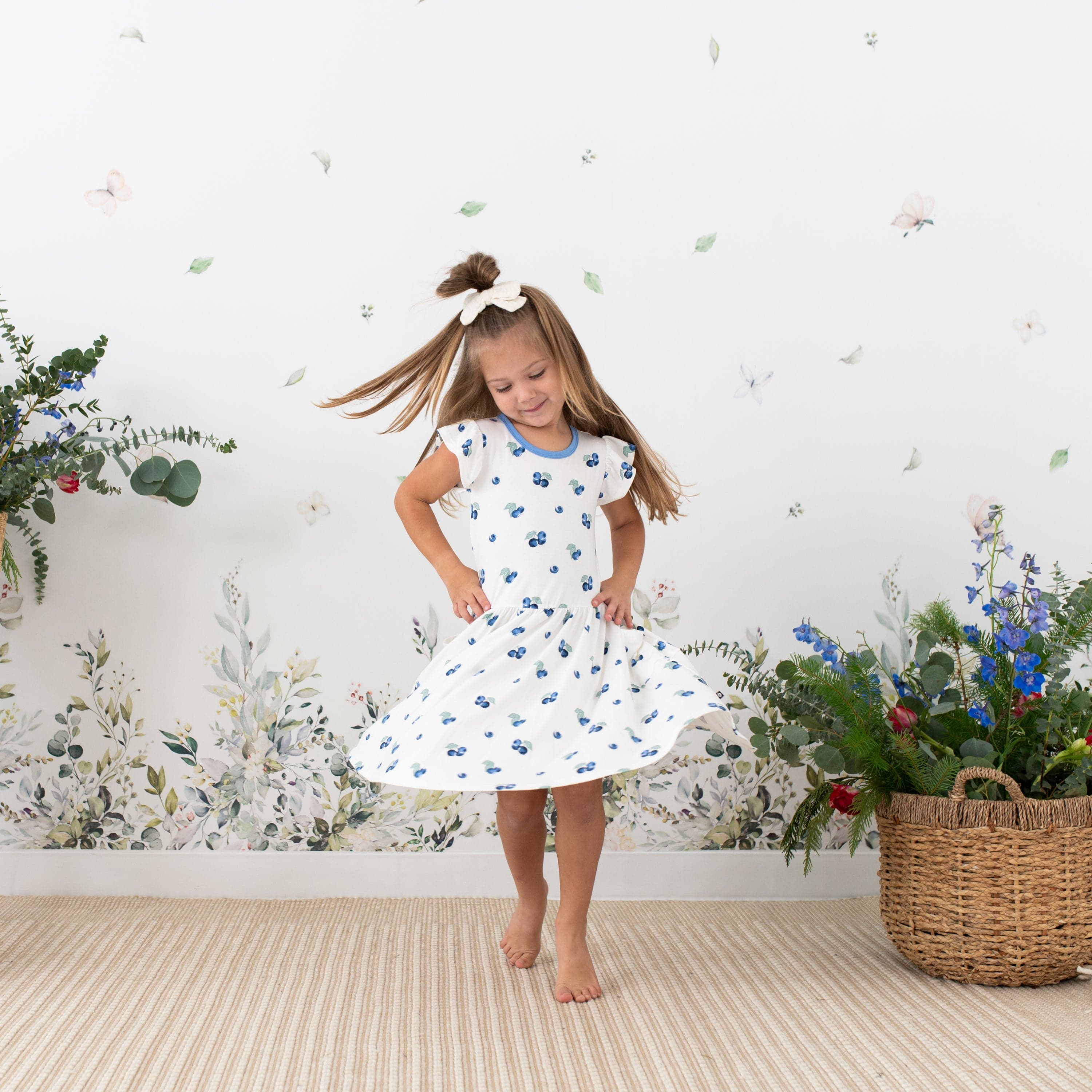 Toddler twirling in Kyte Baby bamboo Pocket Dress in Blueberry