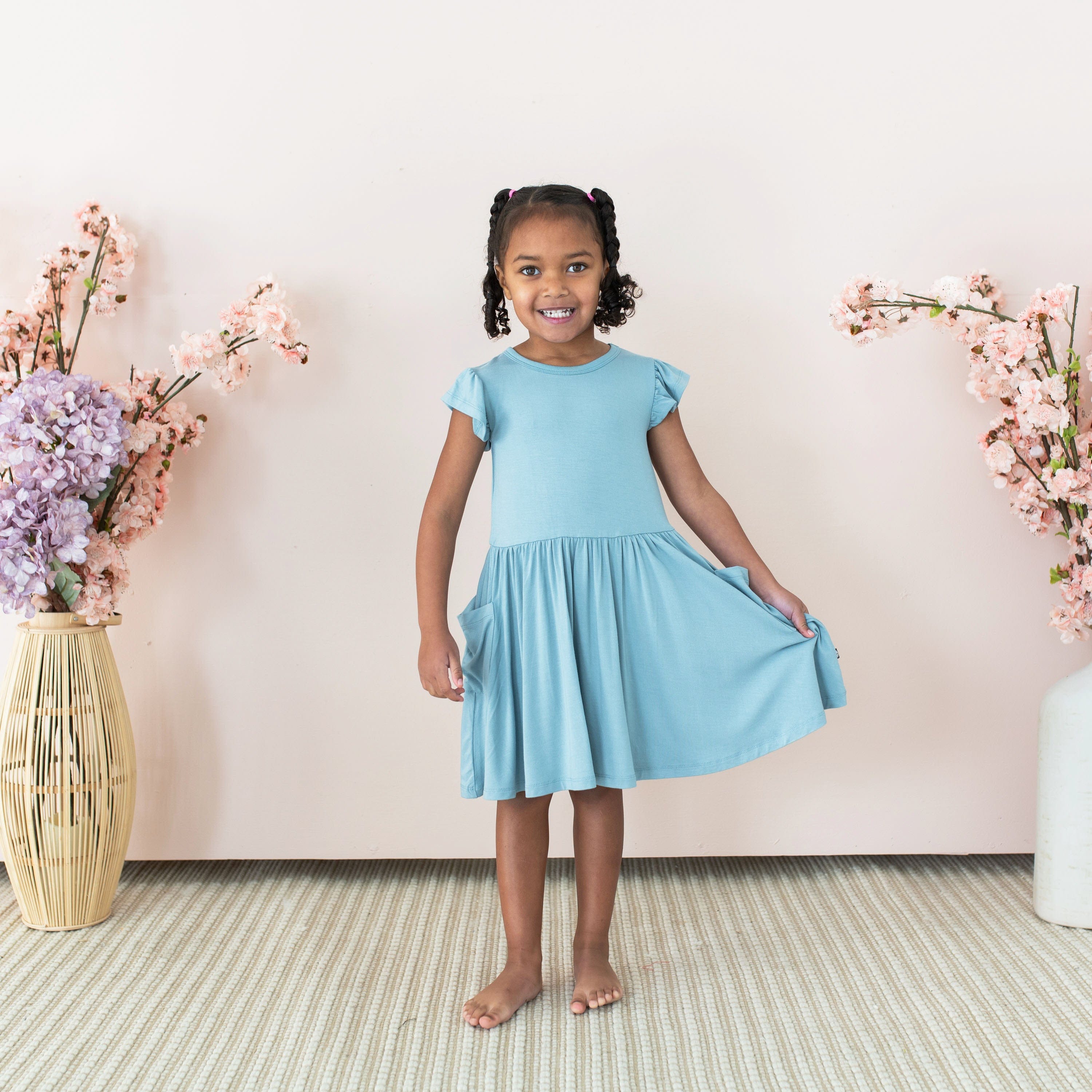 Girl wearing Kyte Baby Pocket Dress in Dusty Blue