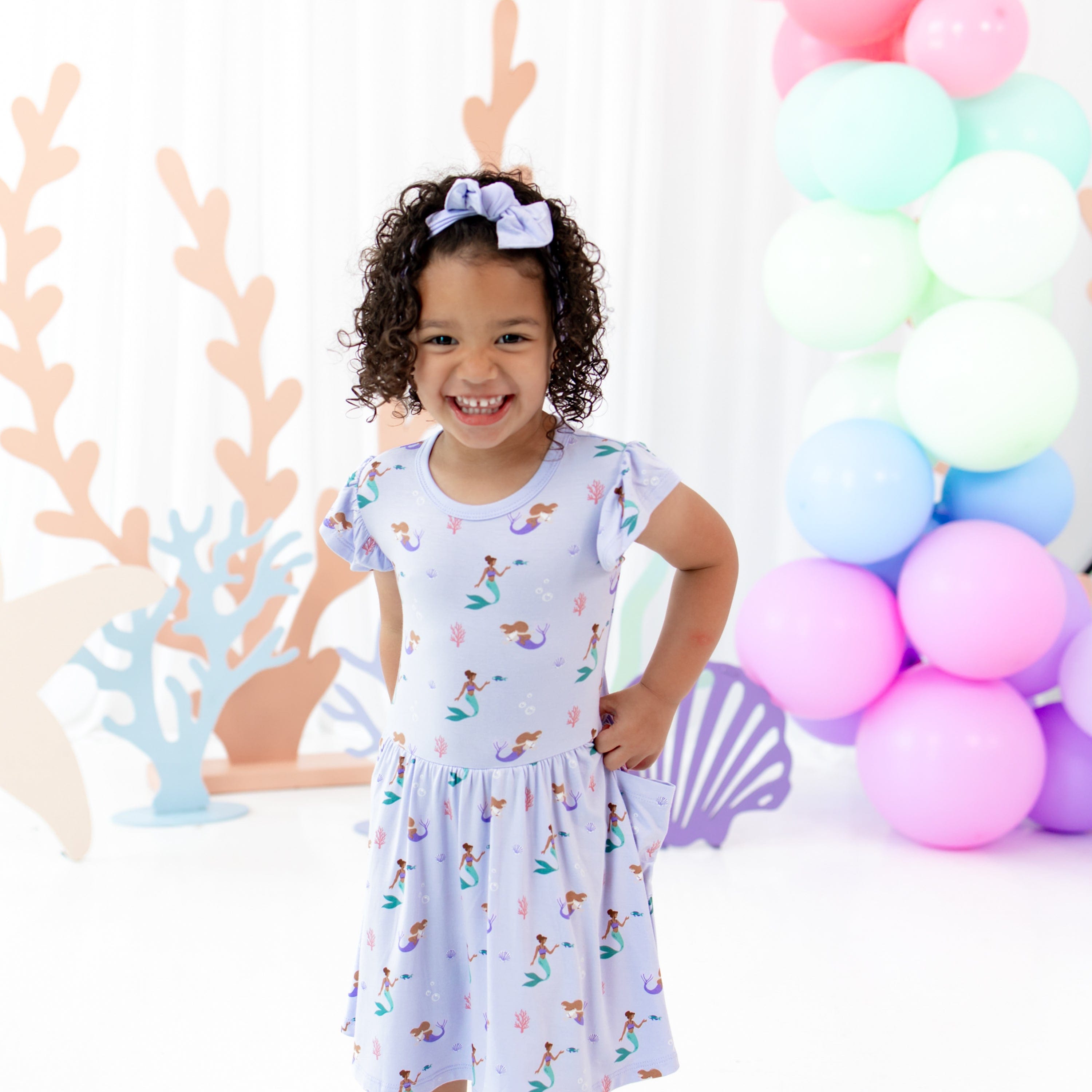 Girl wearing Kyte Baby Pocket Dress in Mermaid