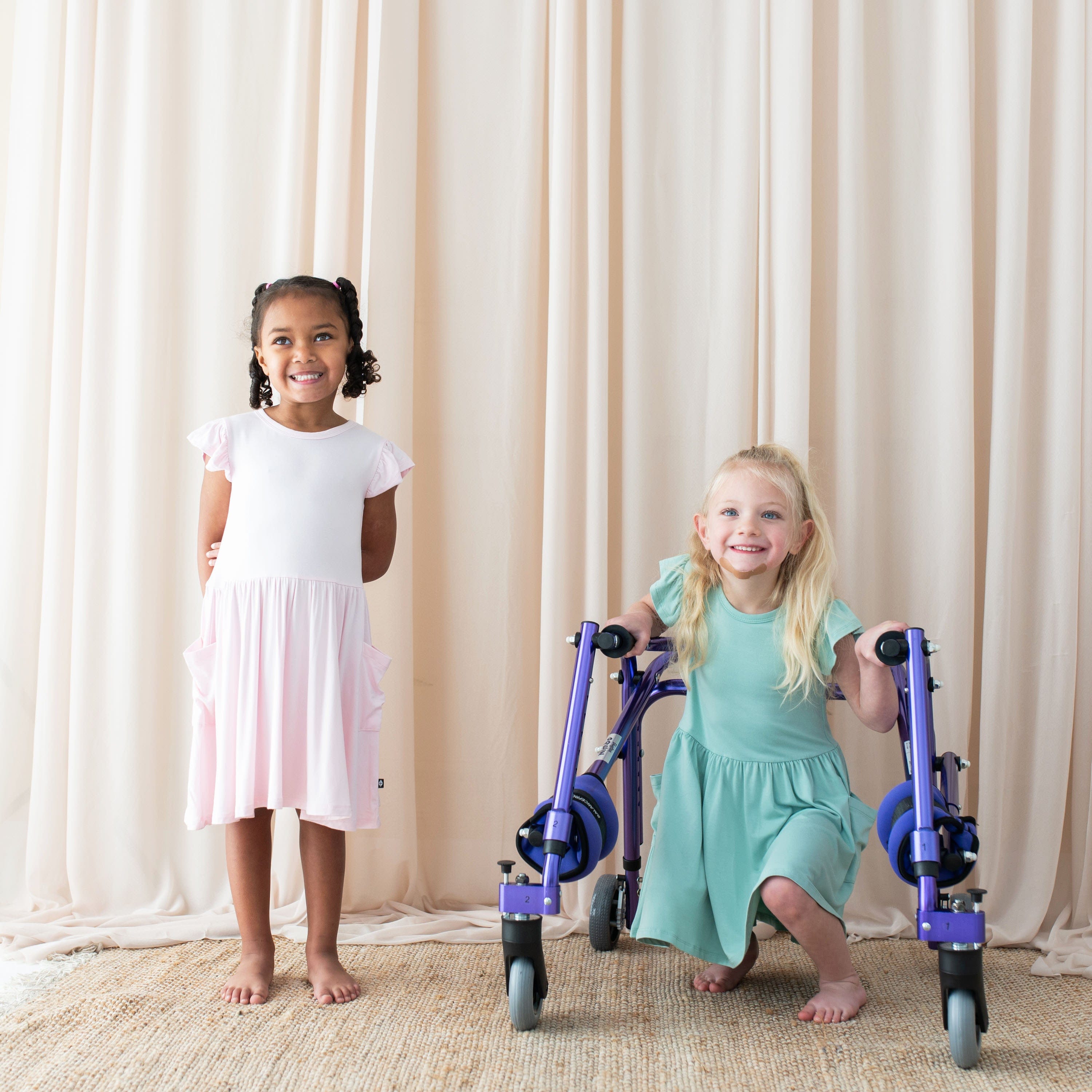 Girls wearing Kyte Baby Toddler Short Sleeve Pocket Dresses in Sakura and Wasabi