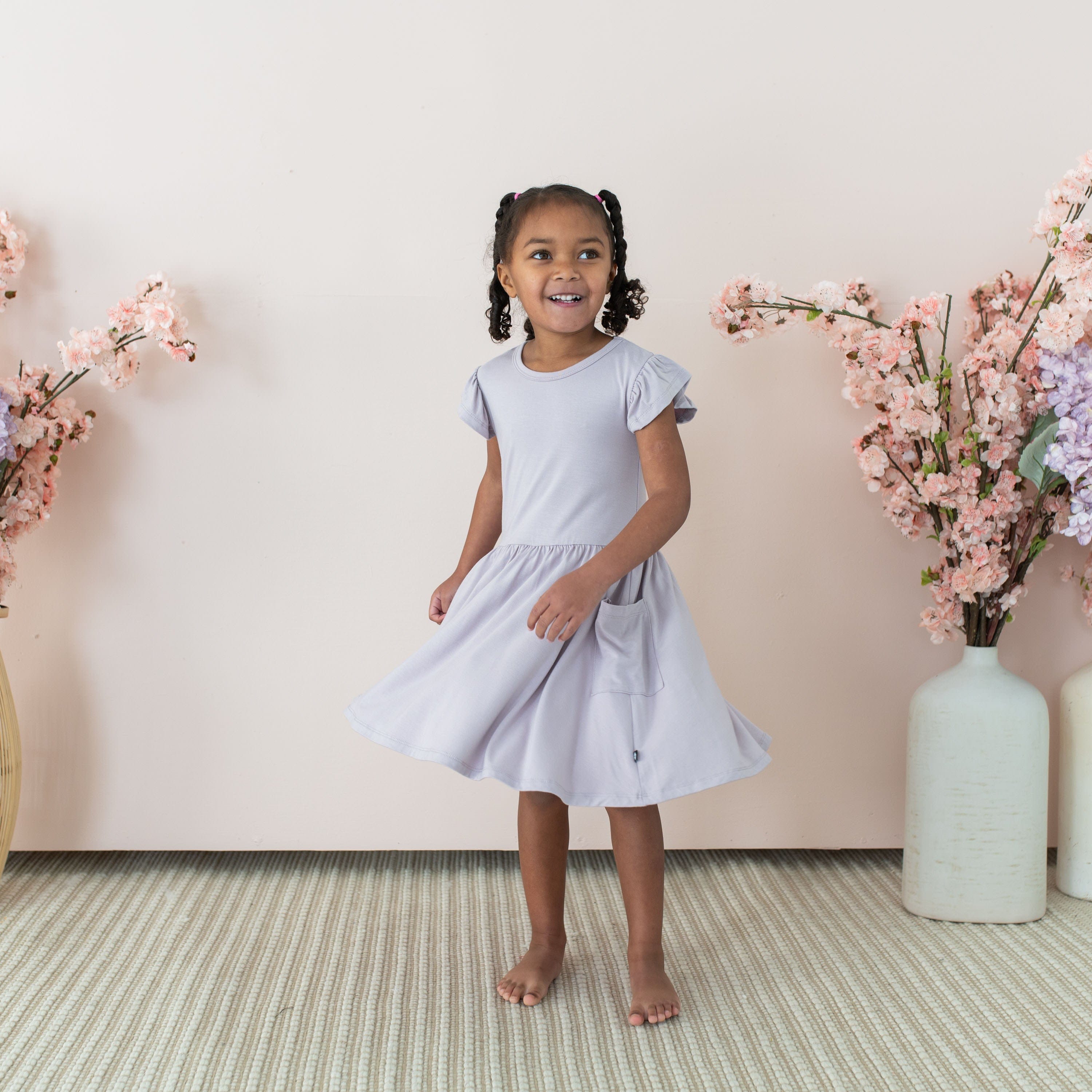 Girl twirling in Kyte Baby bamboo Pocket Dress in Wisteria purple