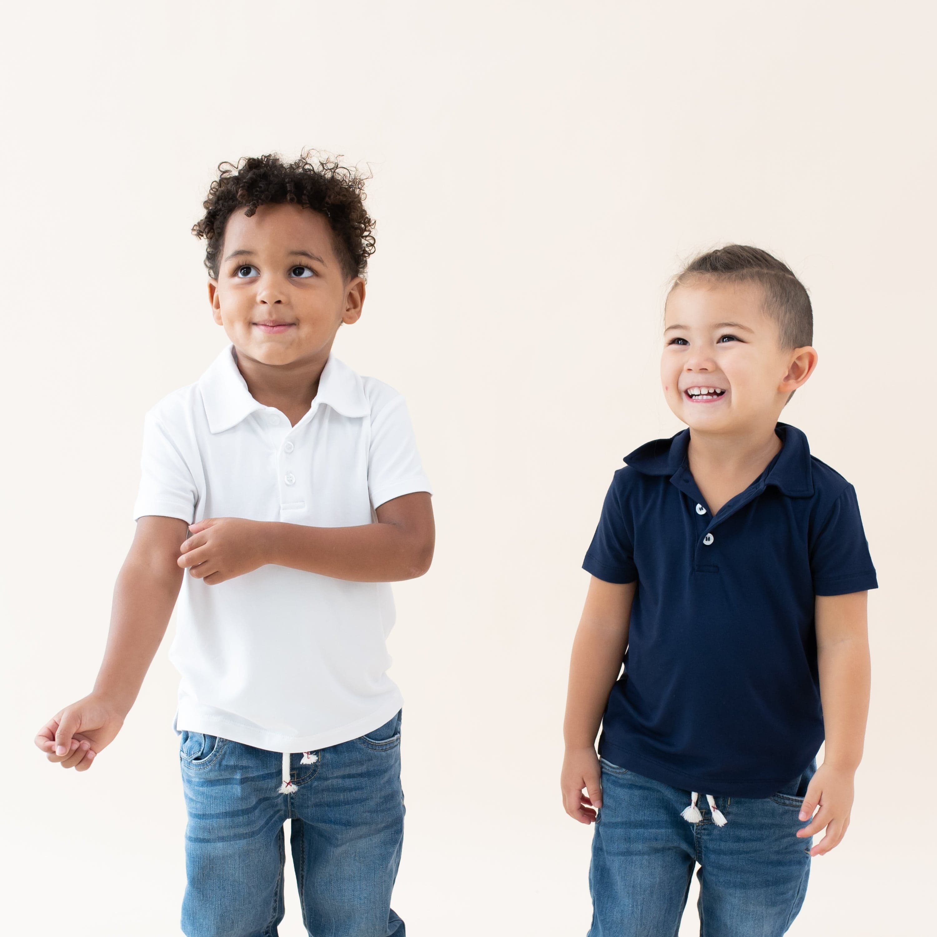 Toddlers wearing Kyte Baby Bamboo Short Sleeve Polos in Snow and Navy