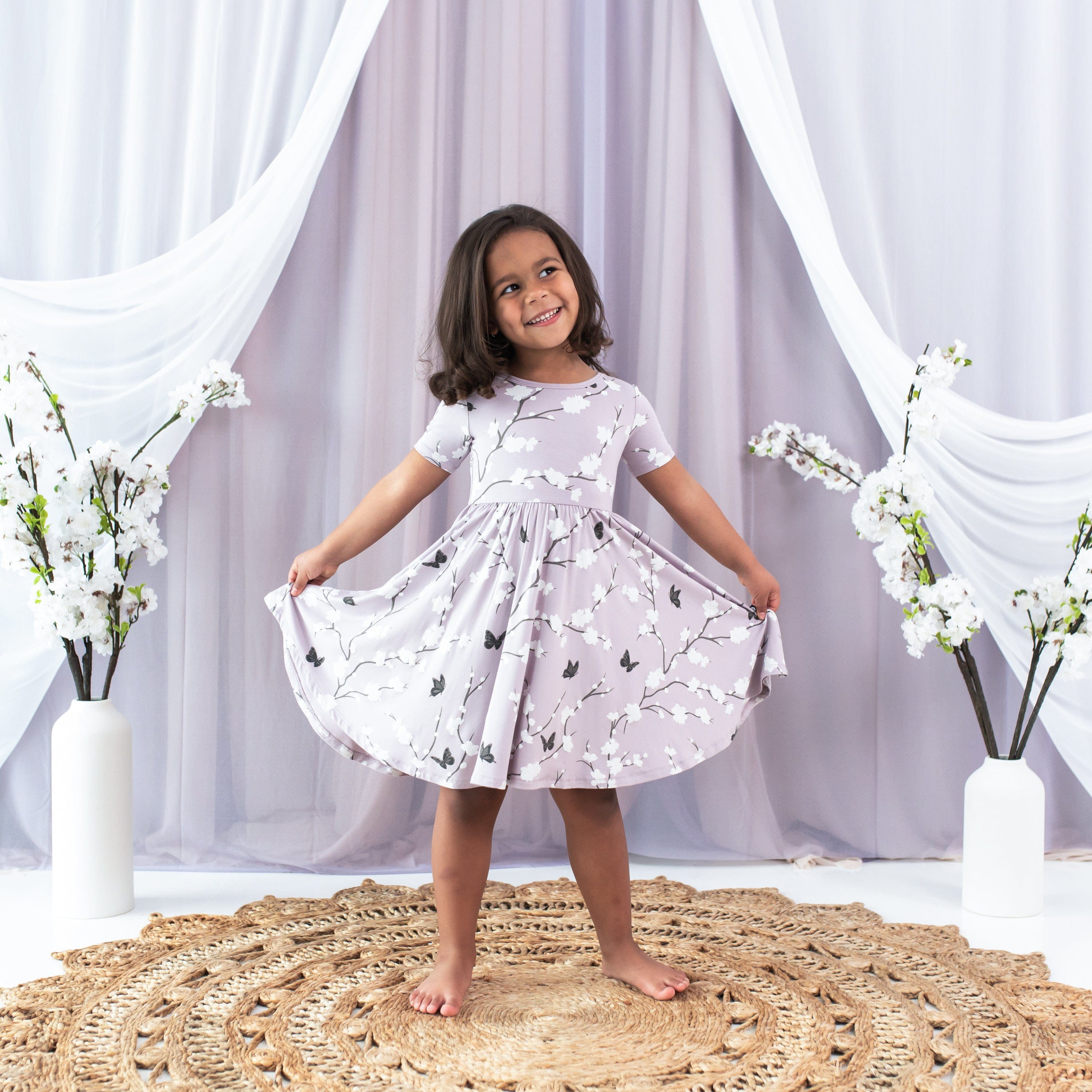 Child wearing Kyte Baby Twirl Dress in Cherry Blossom pattern