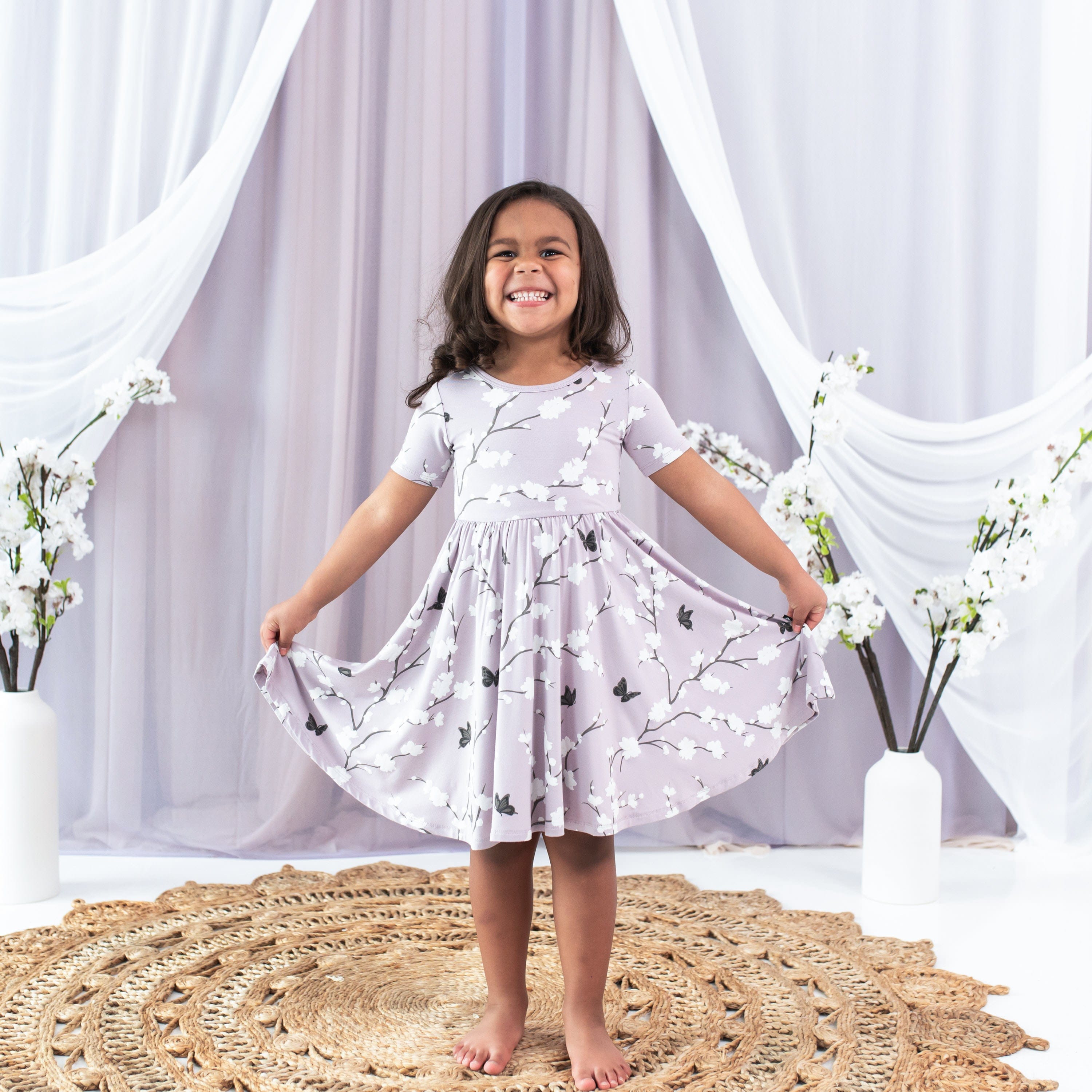 Girl wearing Kyte Baby Twirl Dress in purple Cherry Blossom