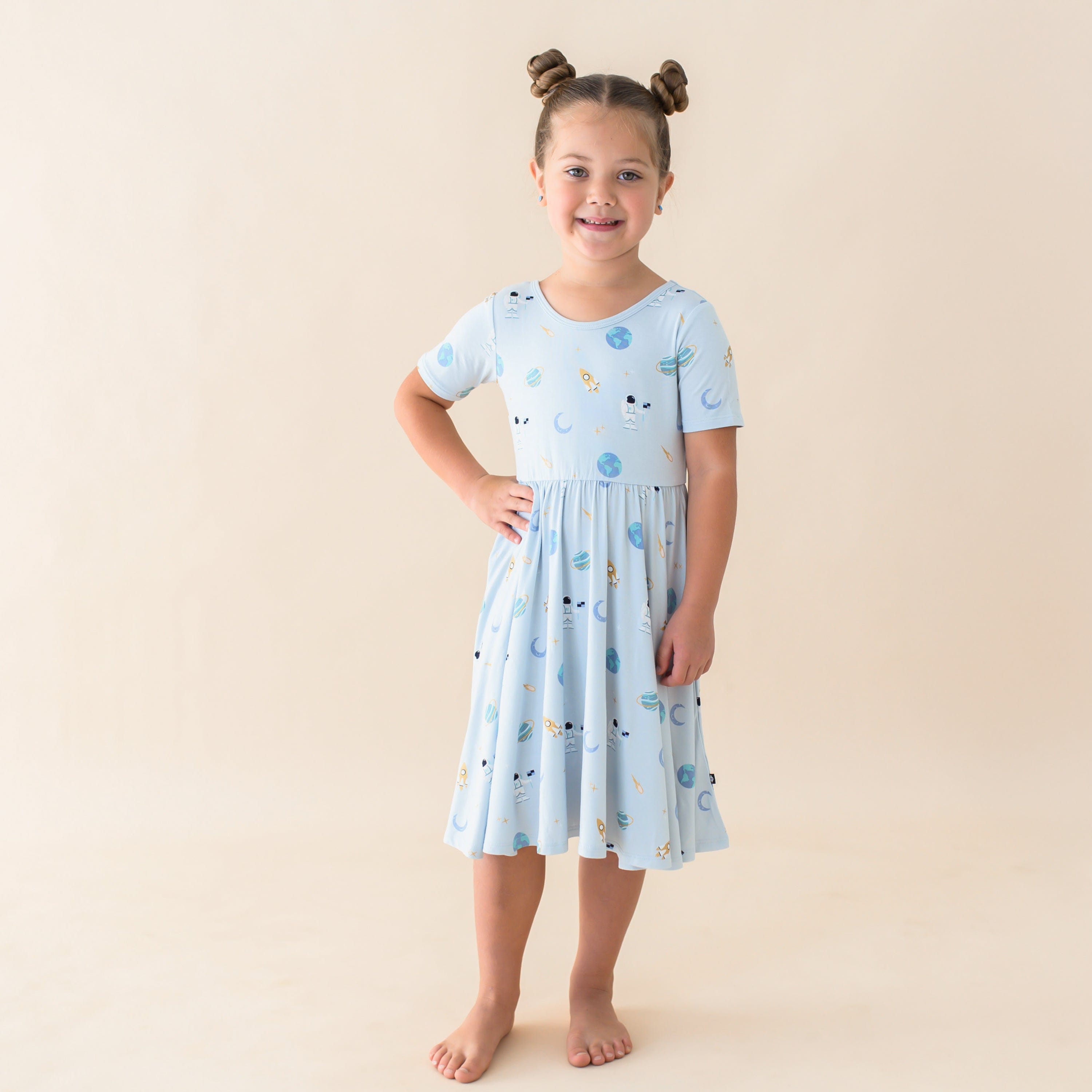 Girl wearing Kyte Baby Short Sleeve Twirl Dress in Ice Space