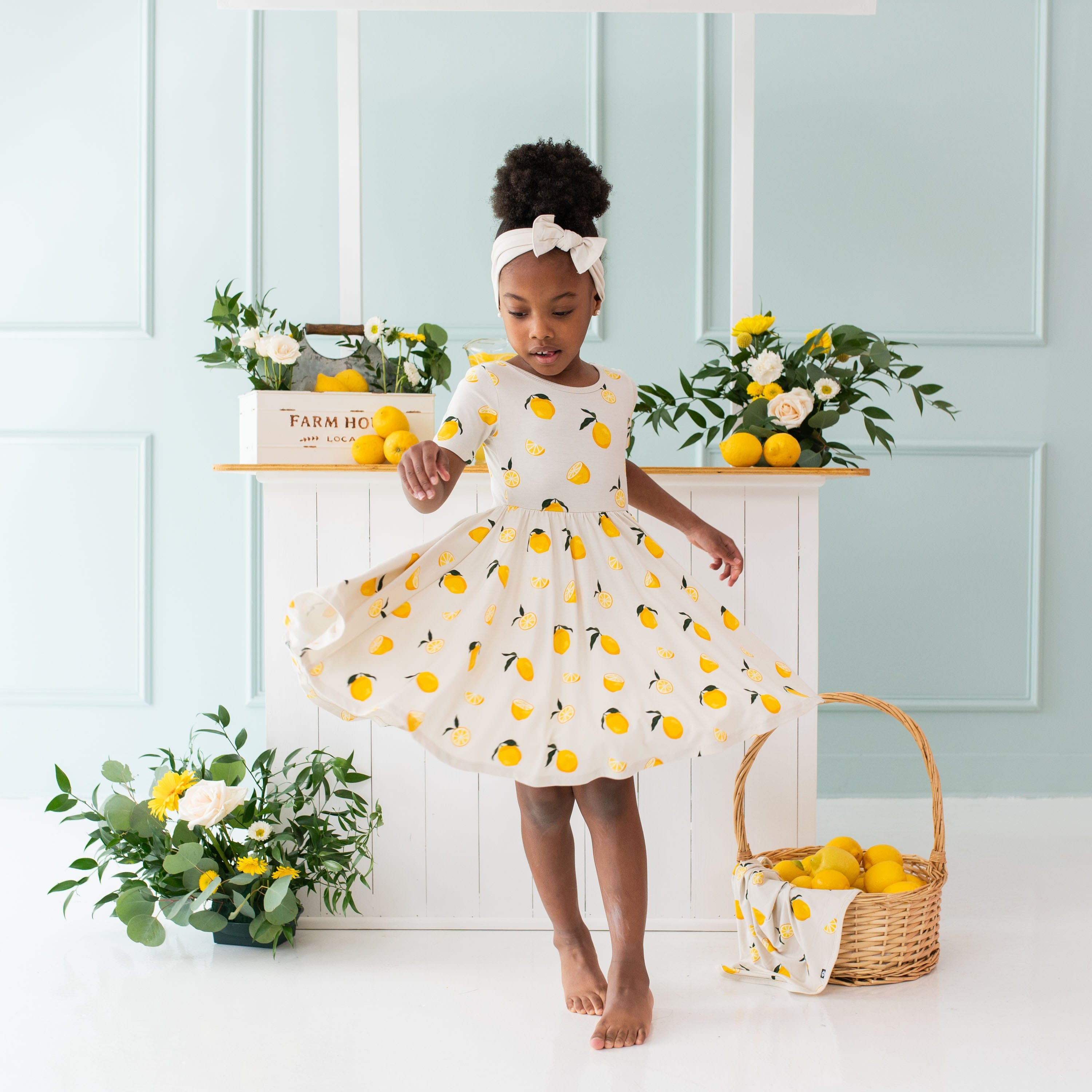 Girl twirling in Kyte Baby Bamboo Twirl Dress in Lemon