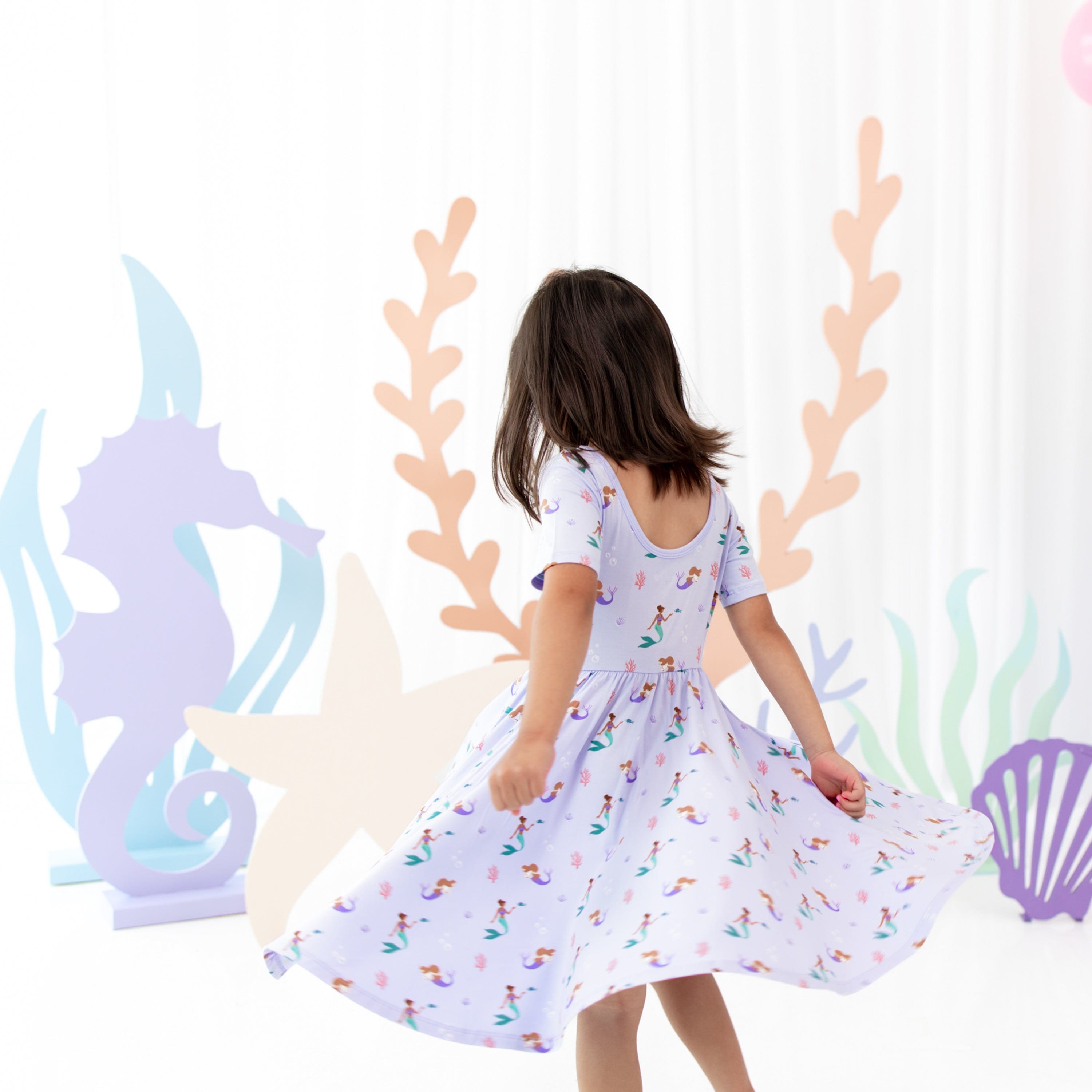 Toddler twirling in Kyte Baby Twirl Dress in Mermaid