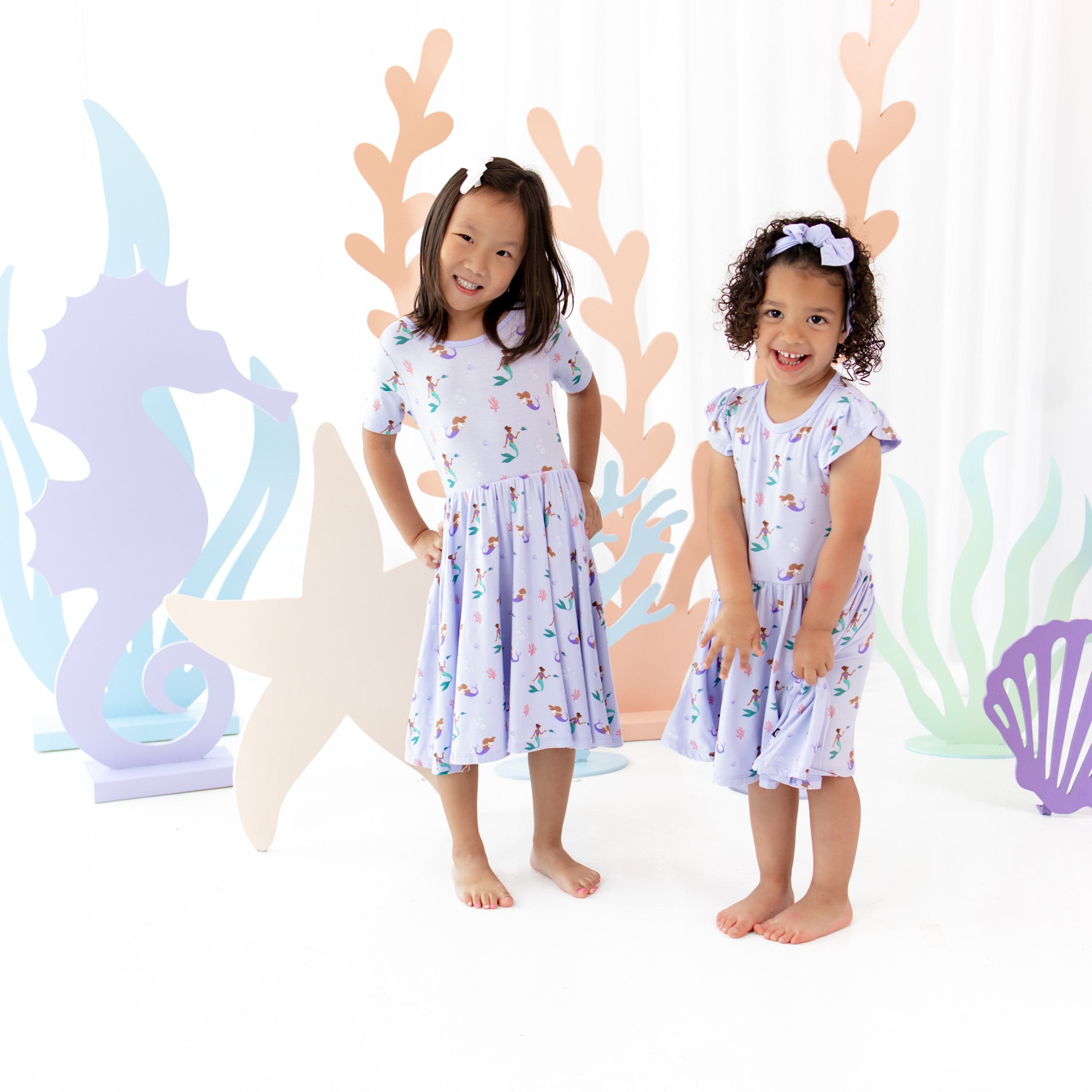 Girls wearing Kyte Baby Short Sleeve Twirl Dresses in Mermaid