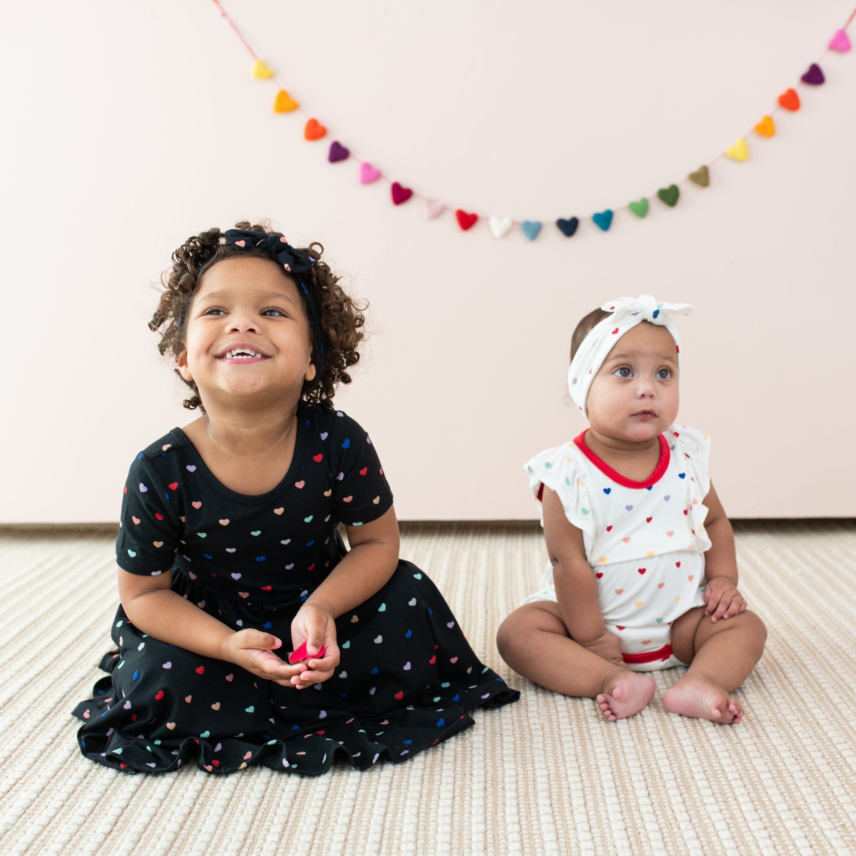 Sisters wearing Kyte Baby Rainbow Heart matching sibling outfits