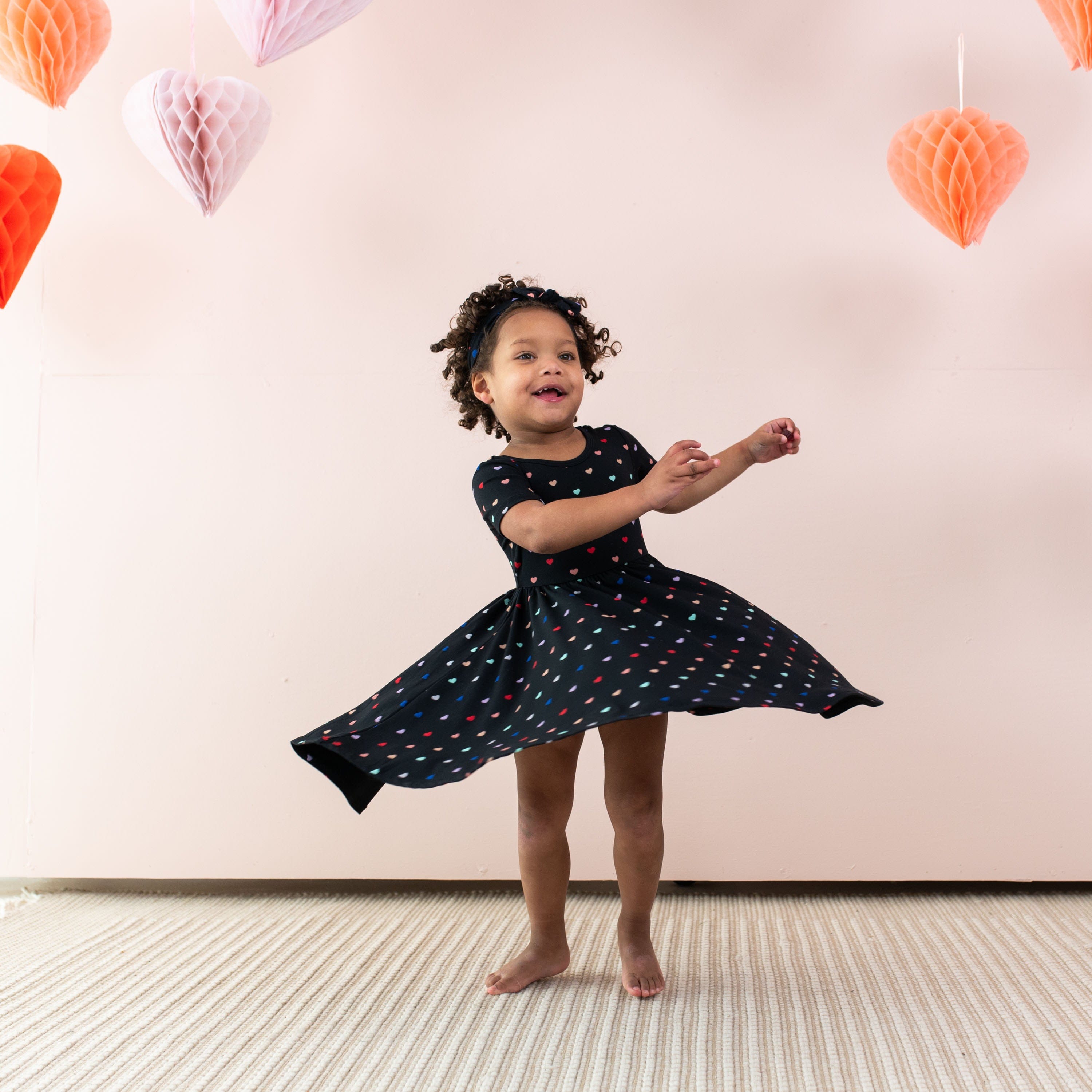 Toddler dancing in Kyte Baby Twirl Dress in Midnight Rainbow Heart