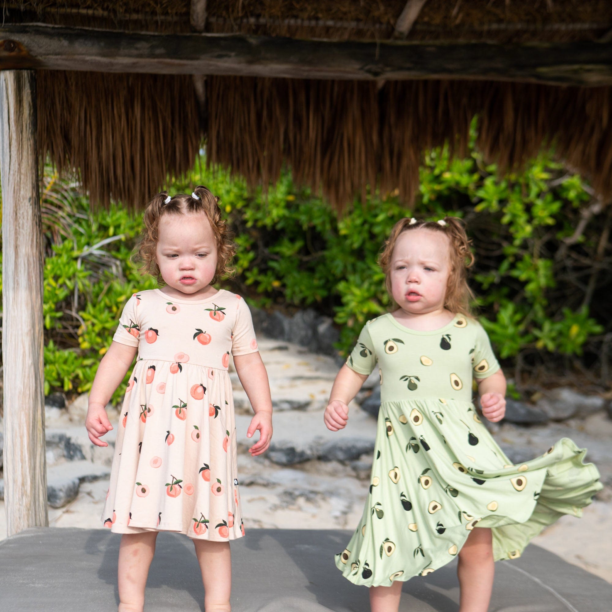 Girls wearing Kyte Baby Twirl Dresses in Peach and Avocado