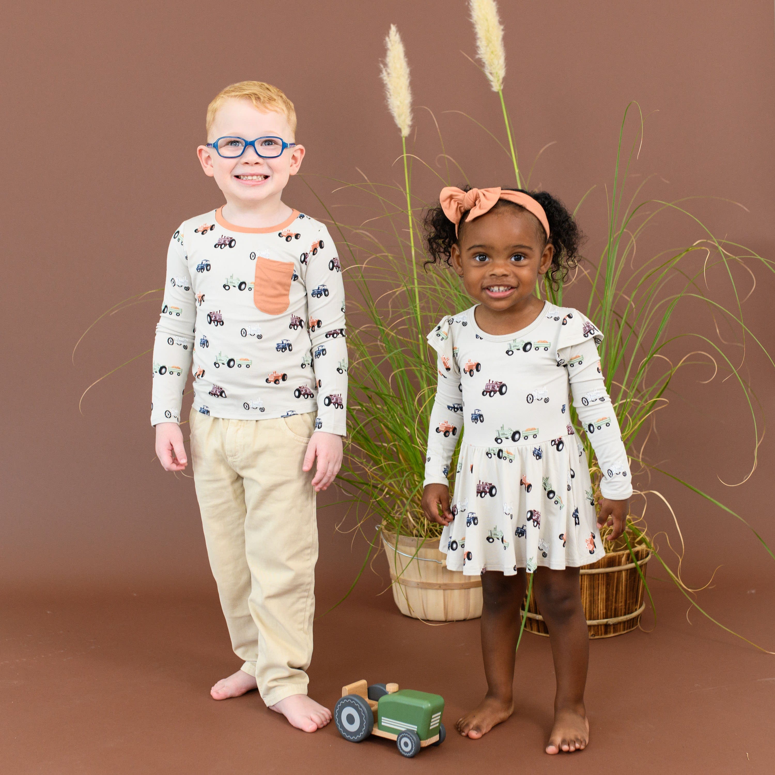 Kids wearing matching Kyte Baby bamboo clothing in Tractor print