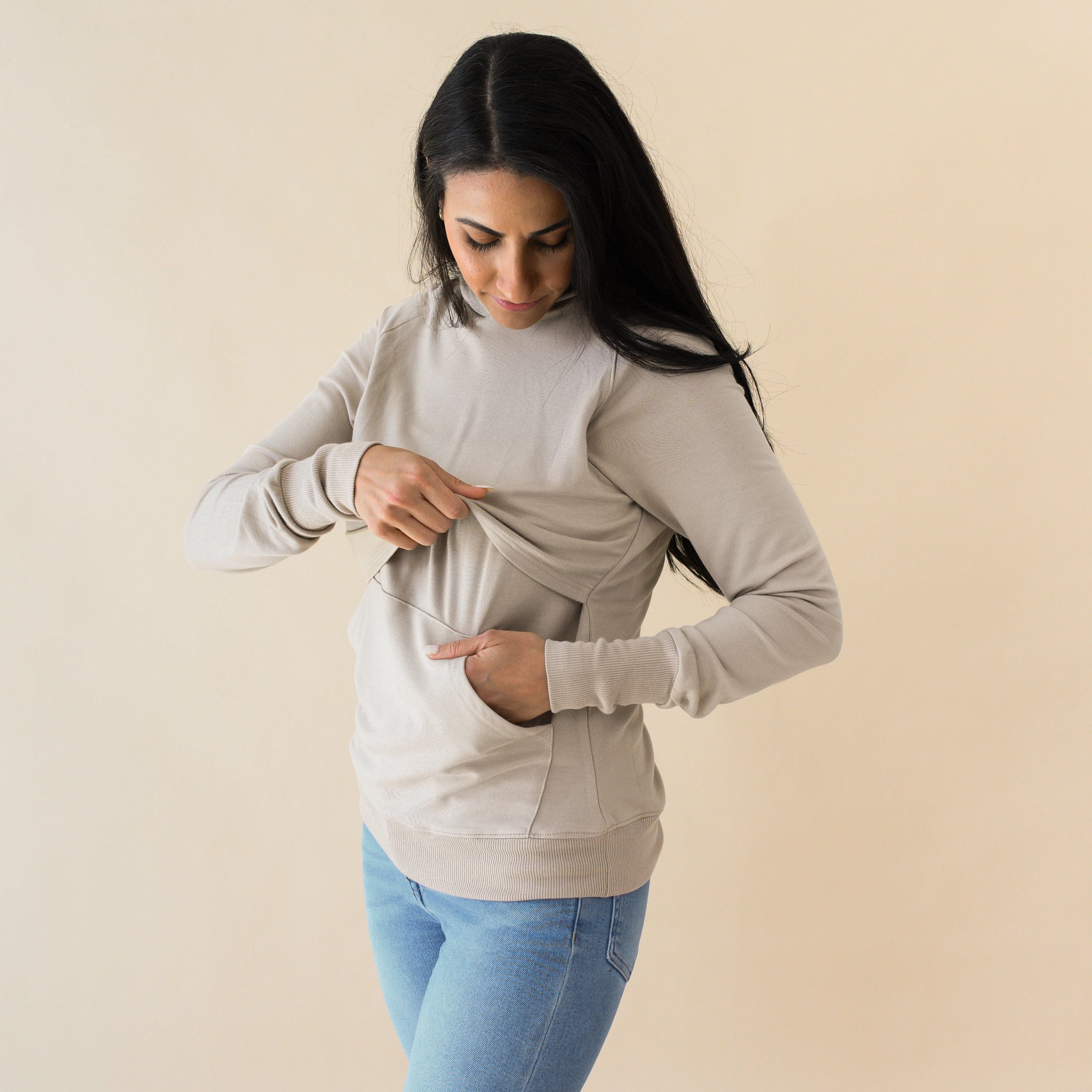 Woman demonstrating function of Kyte Baby Women's French Terry Nursing Hoodie in Almond