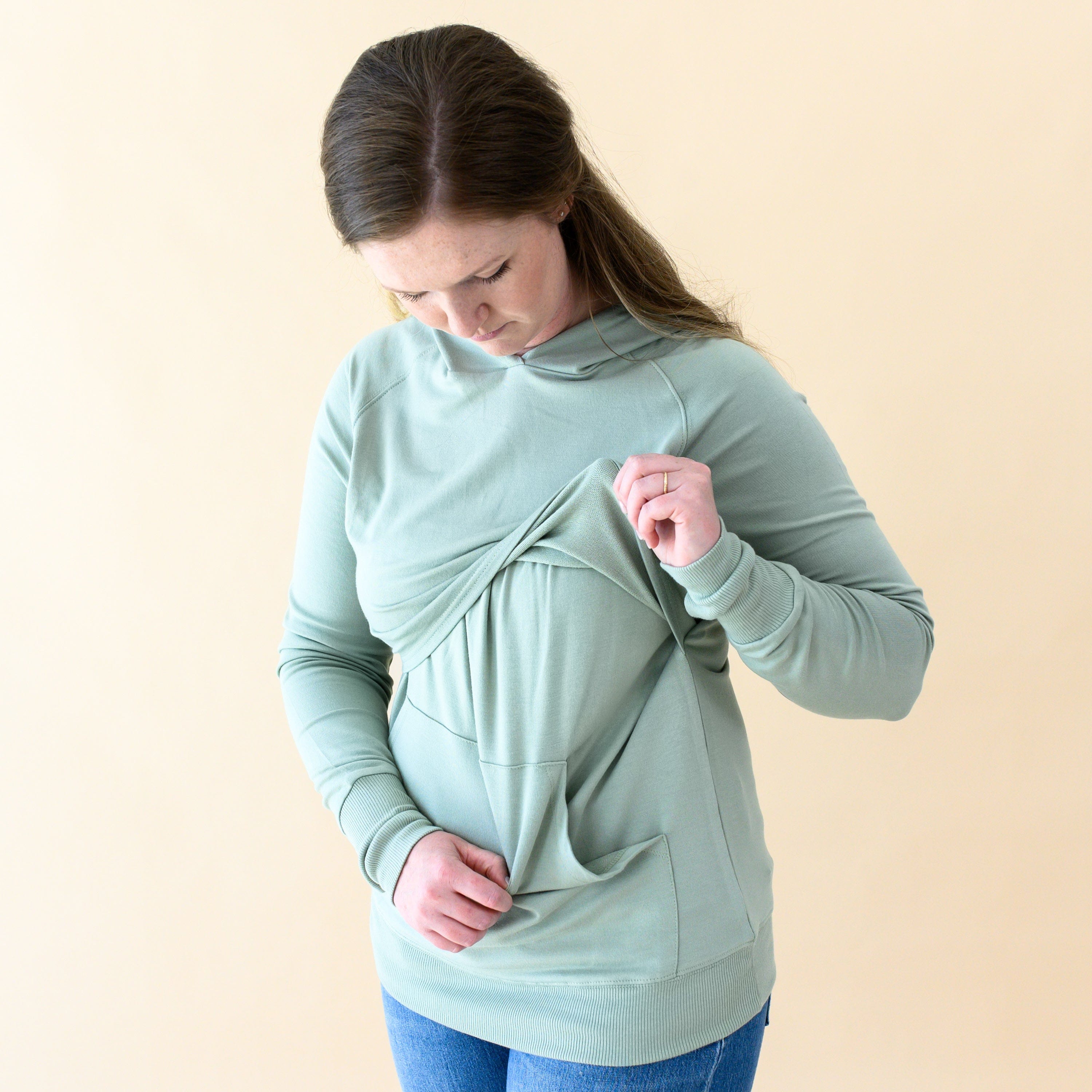 Woman demonstrating function of Kyte Baby Women's French Terry Nursing Hoodie in Thyme