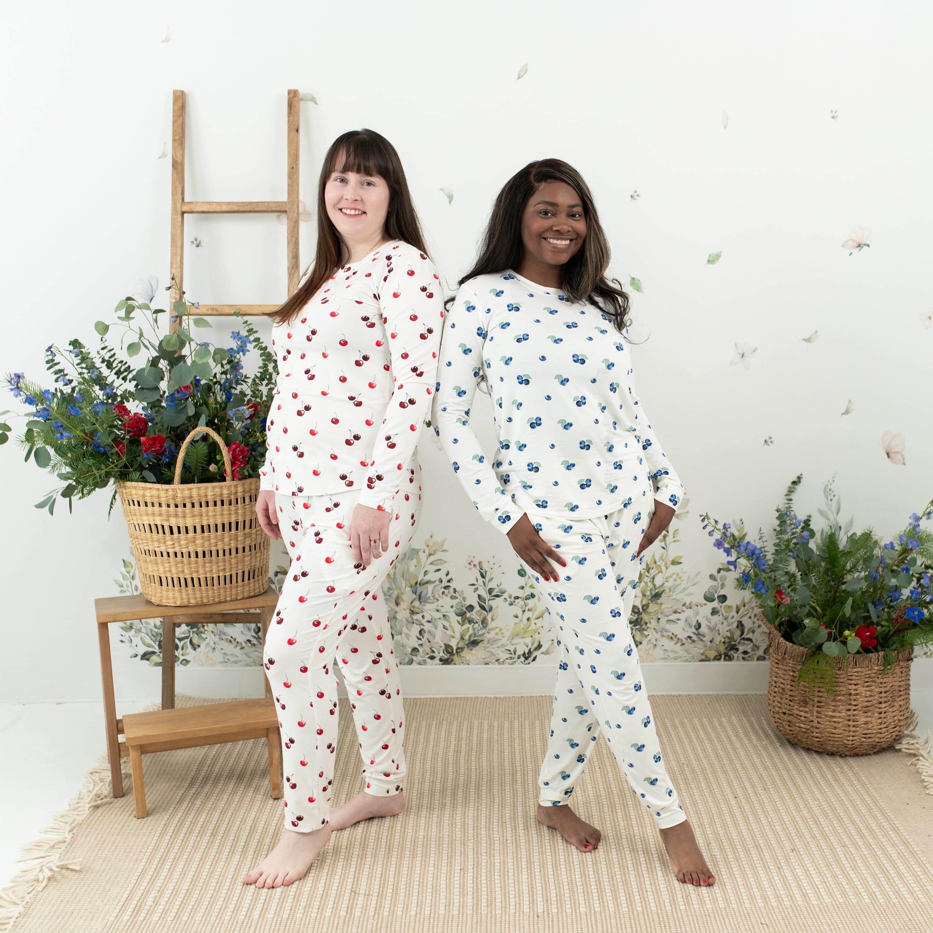 Women wearing Kyte Baby women's jogger pajama set in Cherry and Blueberry prints
