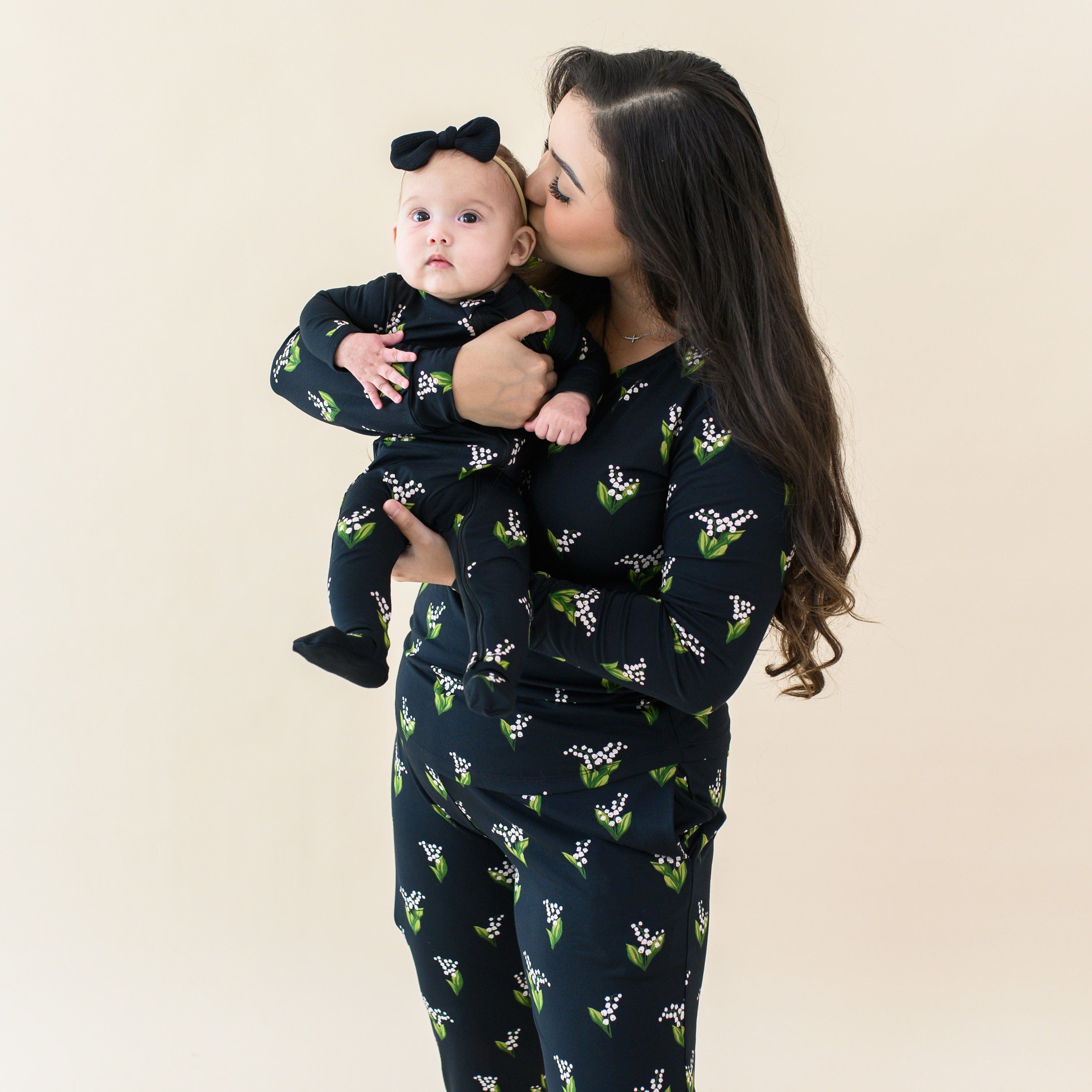 Mom wearing the Women's Jogger Set in Midnight Lily holding daughter wearing the Zippered Footie in Midnight Lily