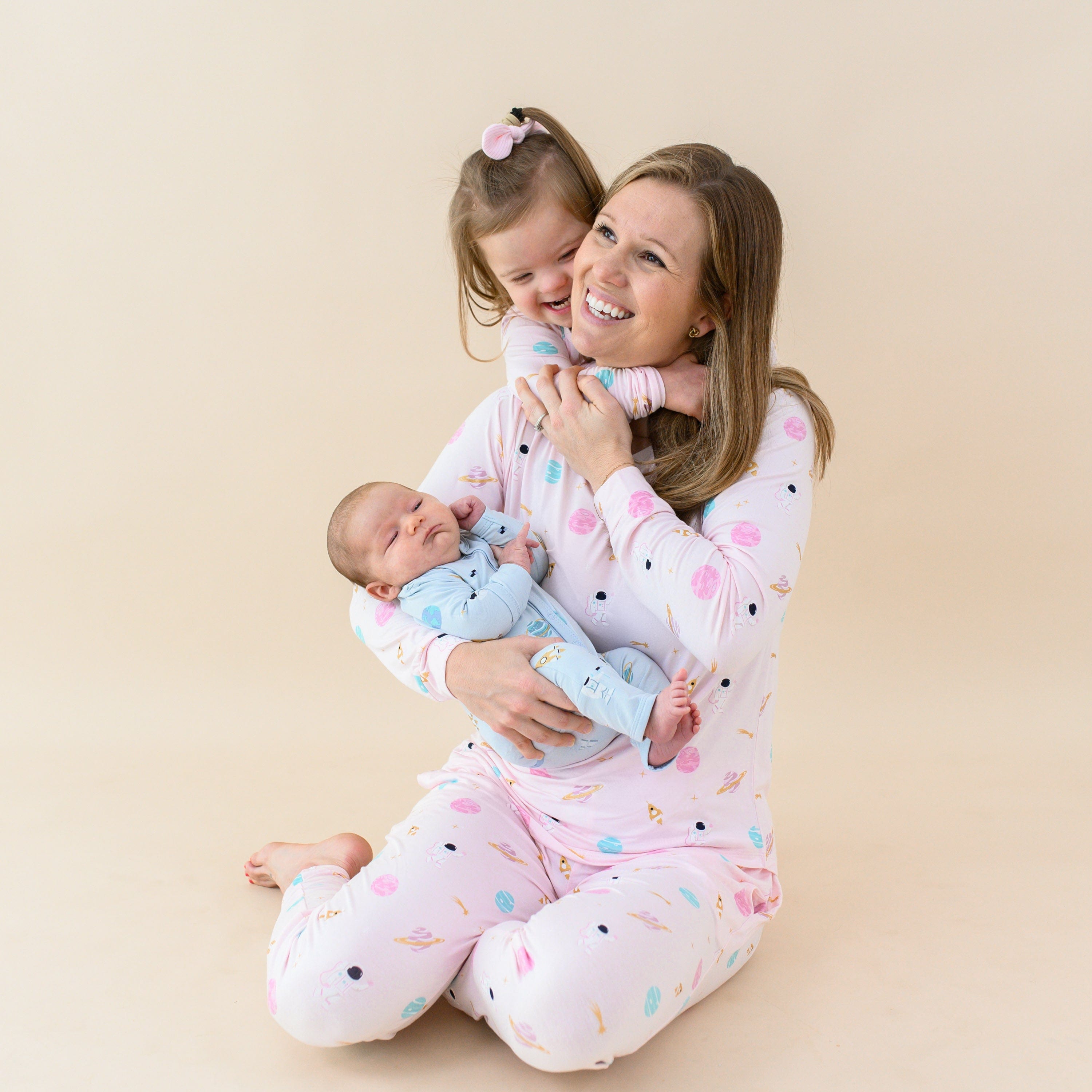 Woman wearing Kyte Baby Women's Jogger Pajama Set in Sakura Space with kids in matching family pjs