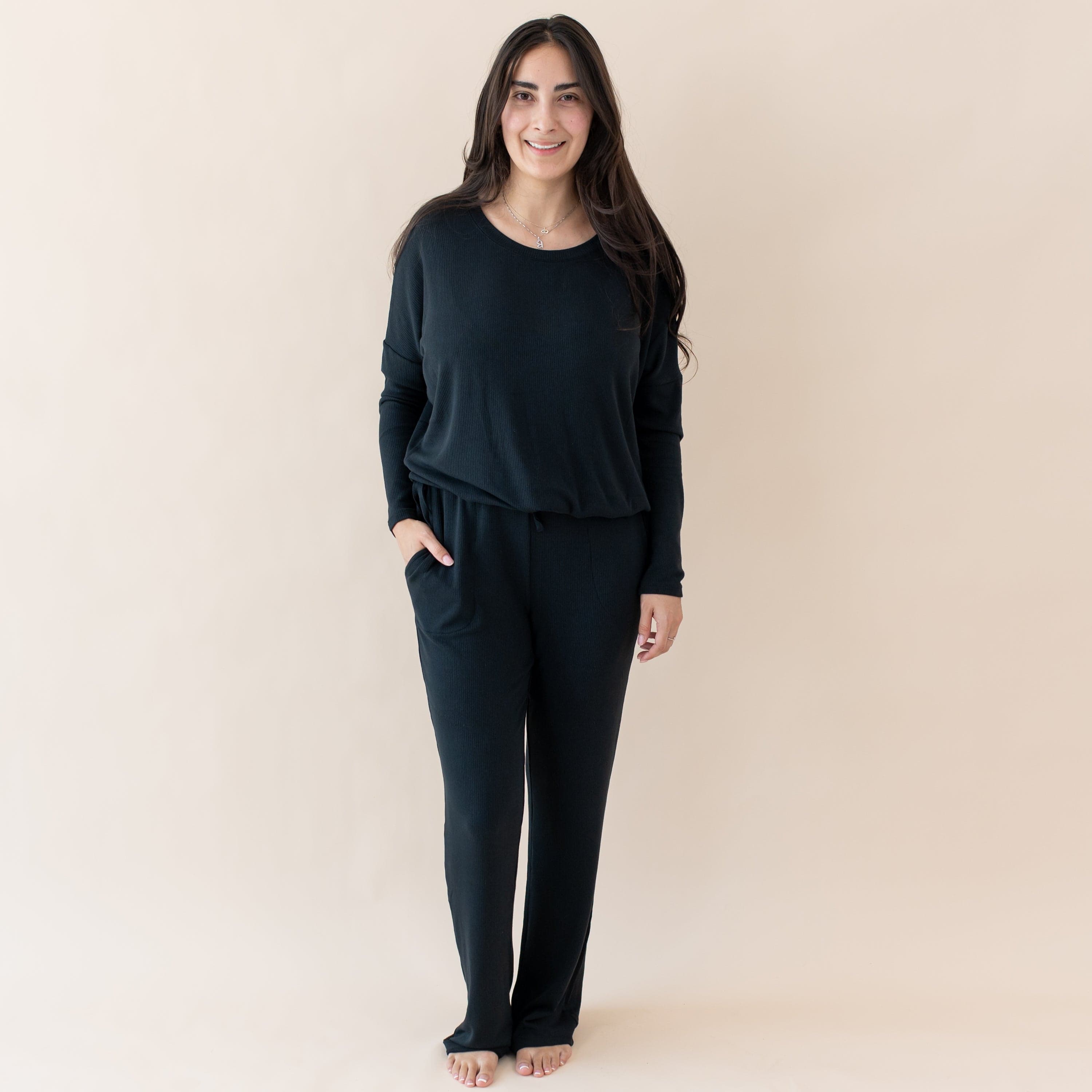 Woman wearing Kyte Baby Women's Ribbed Long Sleeve Drop Shoulder Top and High Waisted Wide Leg Pants in Midnight black