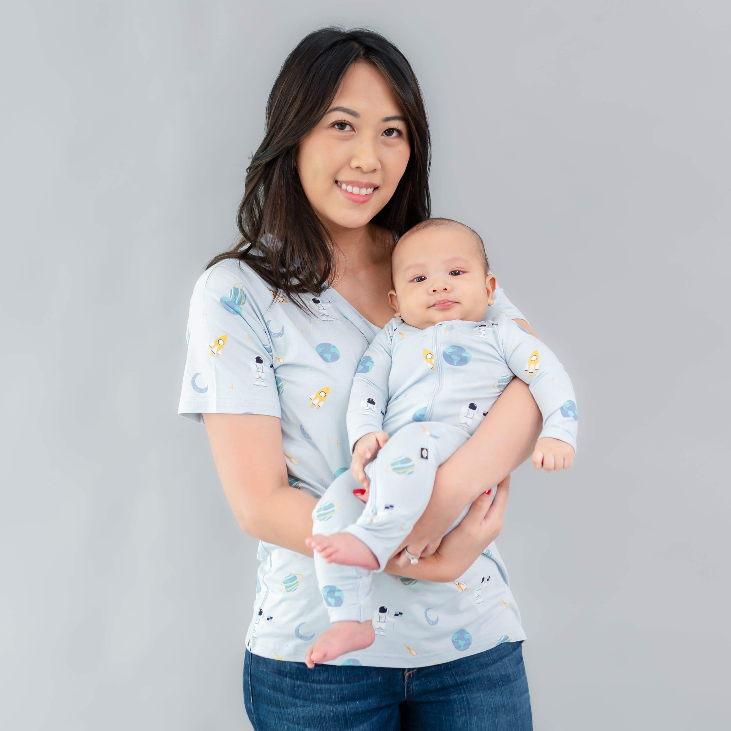 Woman wearing Kyte Baby Women's Relaxed Fit V-Neck in Ice Space holding infant in matching romper
