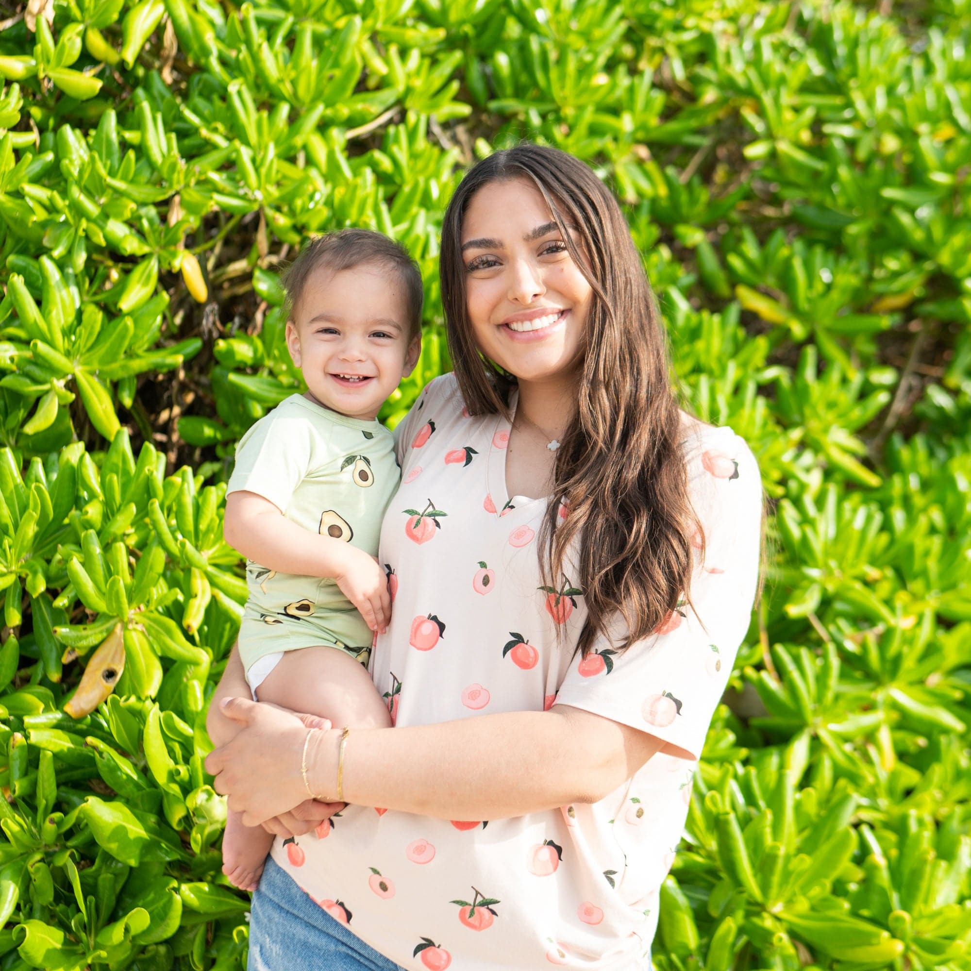 Woman wearing Kyte Baby Women's Relaxed Fit V-Neck tee in Peach holding toddler