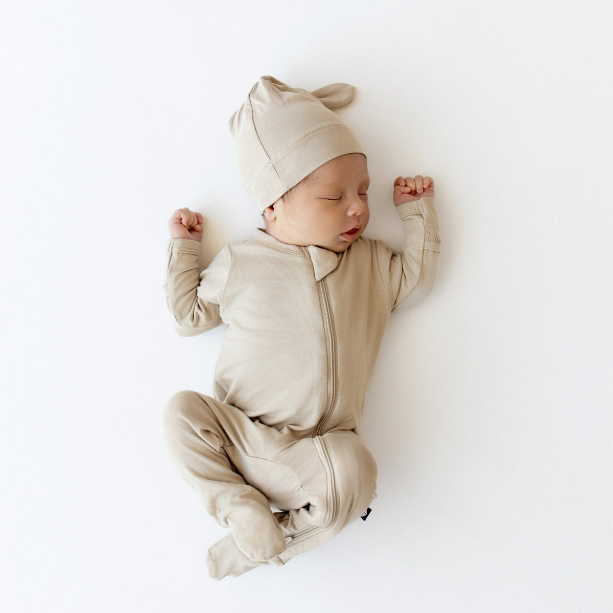 Newborn wearing Kyte Baby Zippered Footie in Almond