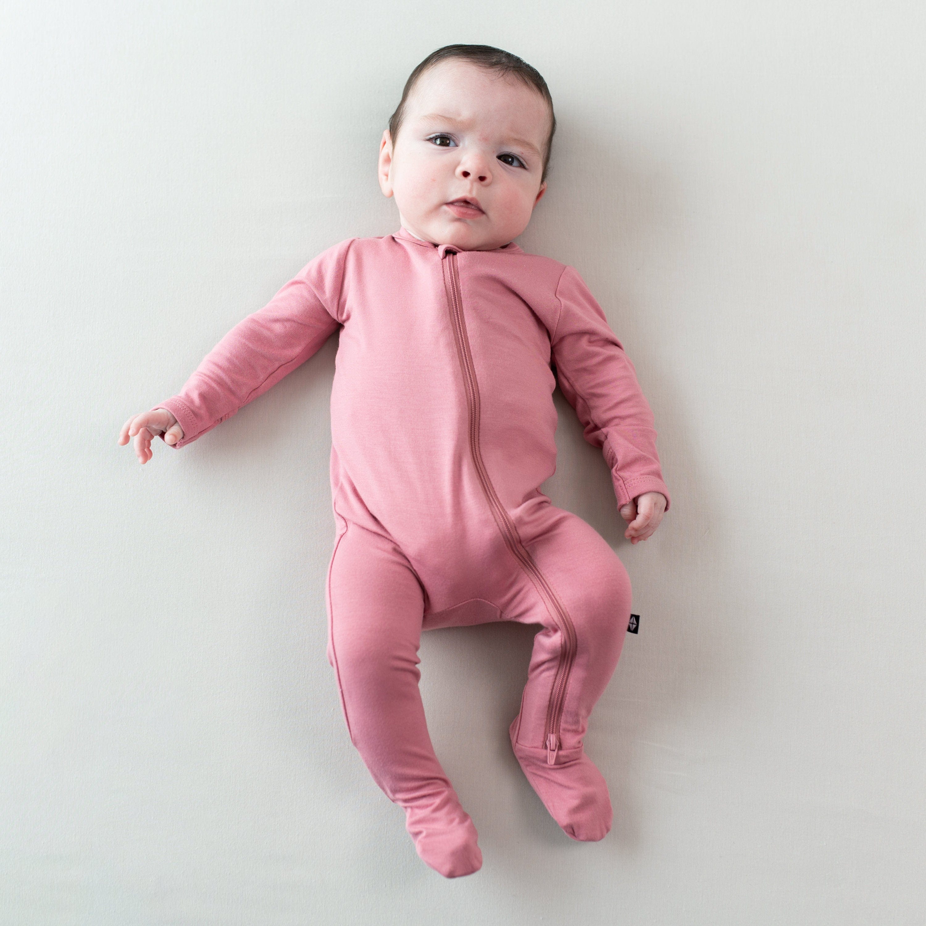 Infant wearing Kyte Baby breathable bamboo Zippered Footie in Apple Blossom pink