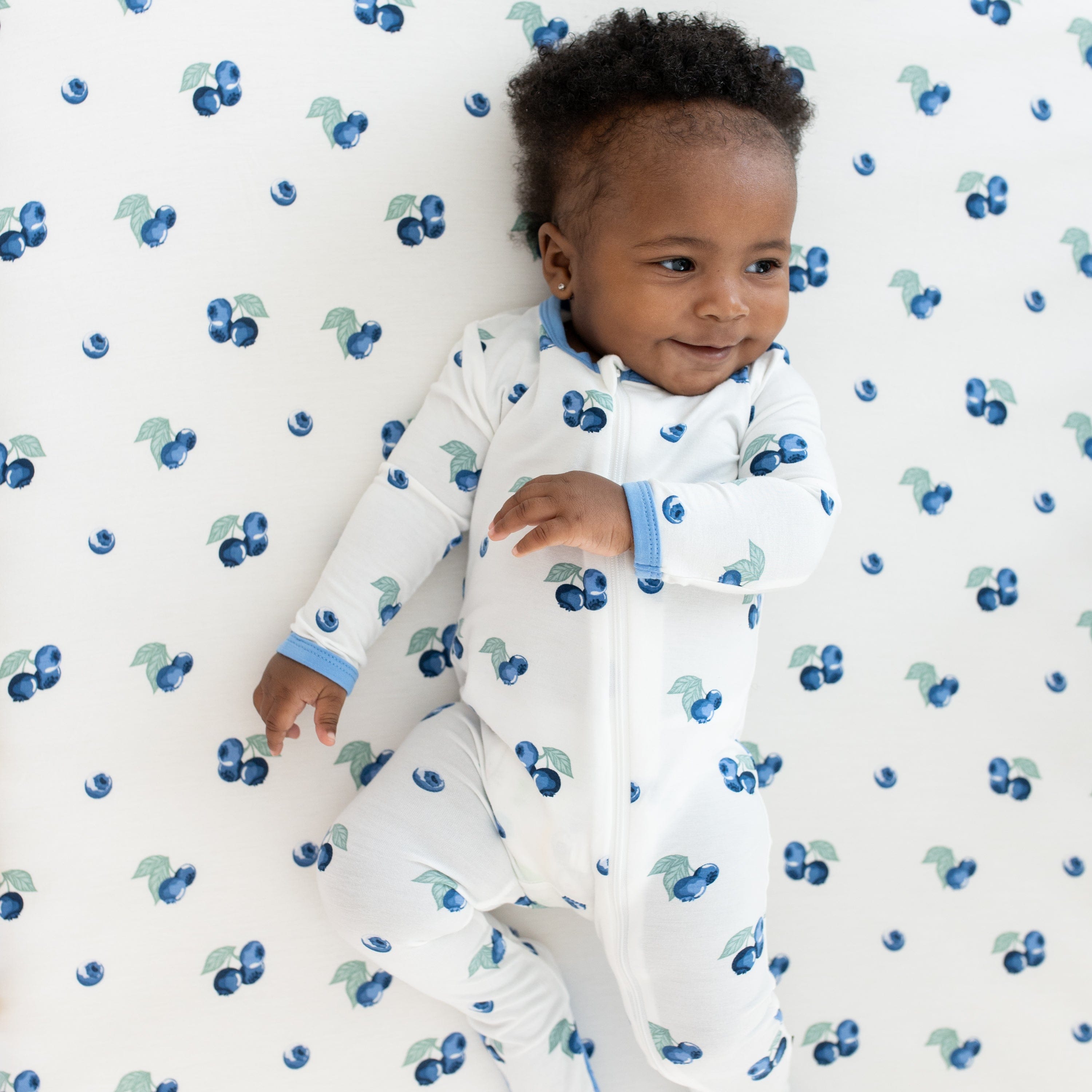 Infant wearing Kyte Baby Zippered Footie pajamas in Blueberry pattern