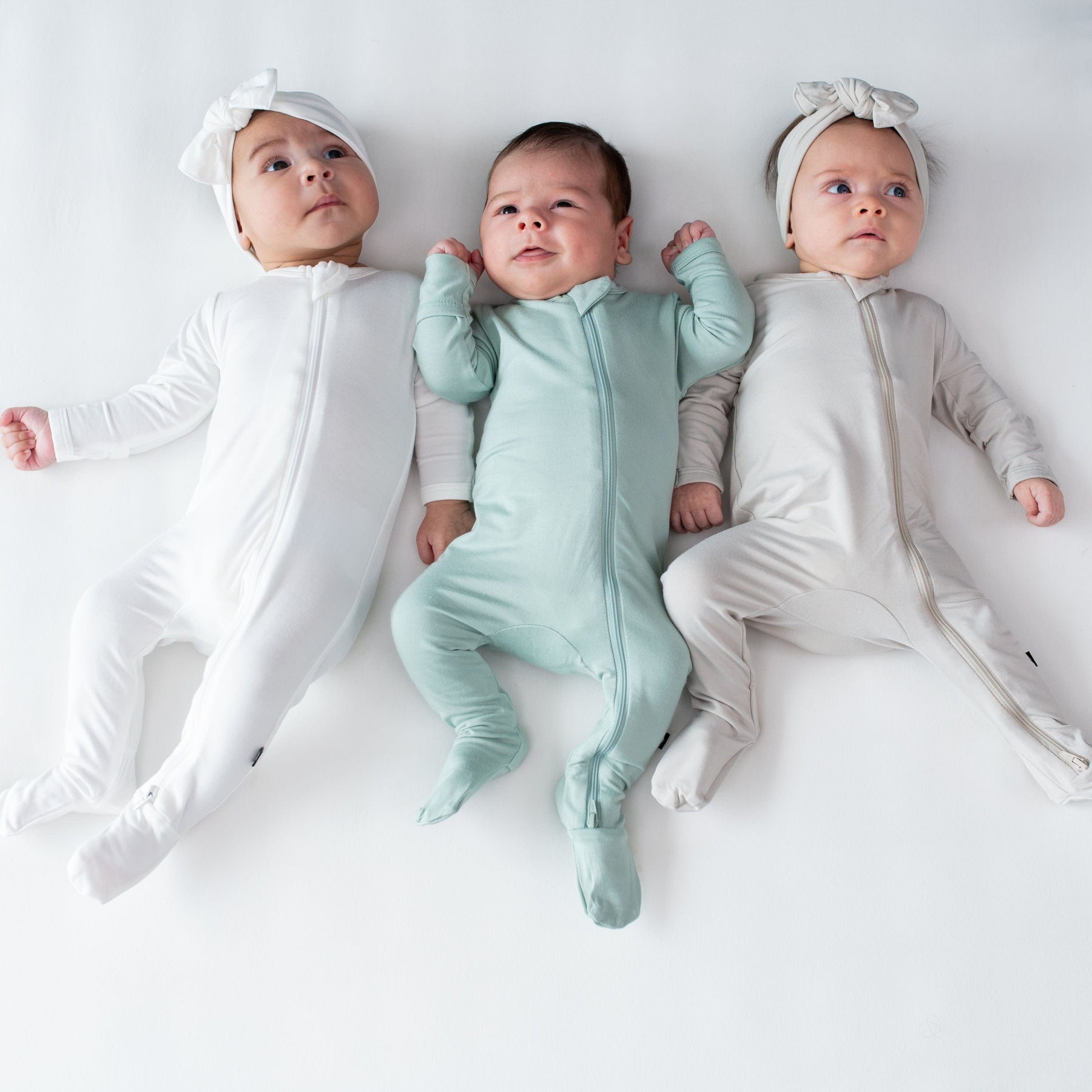 Babies wearing Kyte Baby bamboo zippered footie pajamas