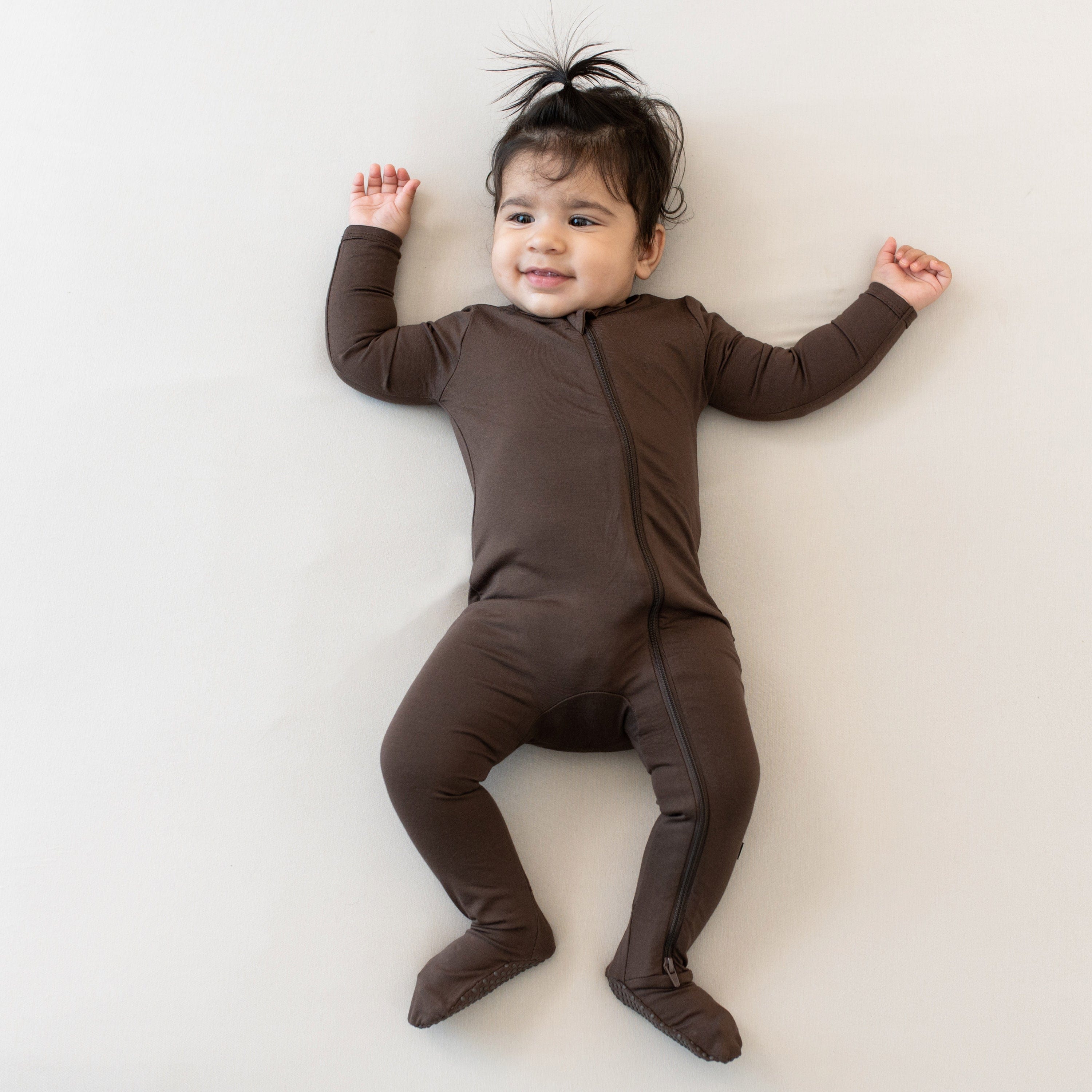 Infant laying down wearing the Zippered Footie in Espresso