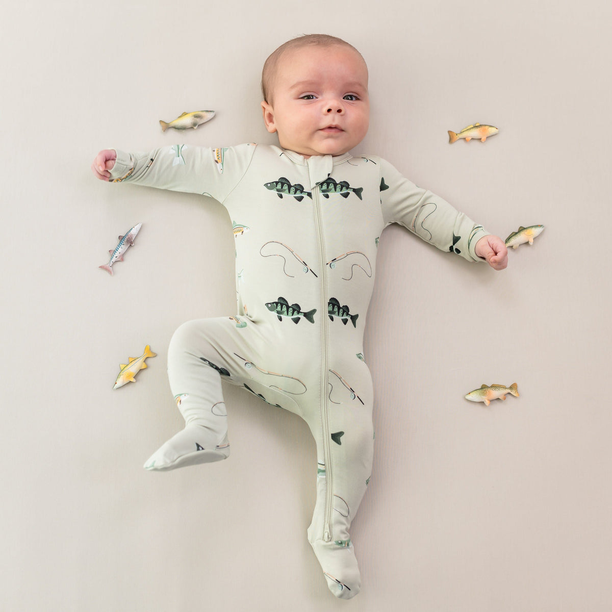 Infant wearing the Zippered Footie in Fishing surrounded by toy fish
