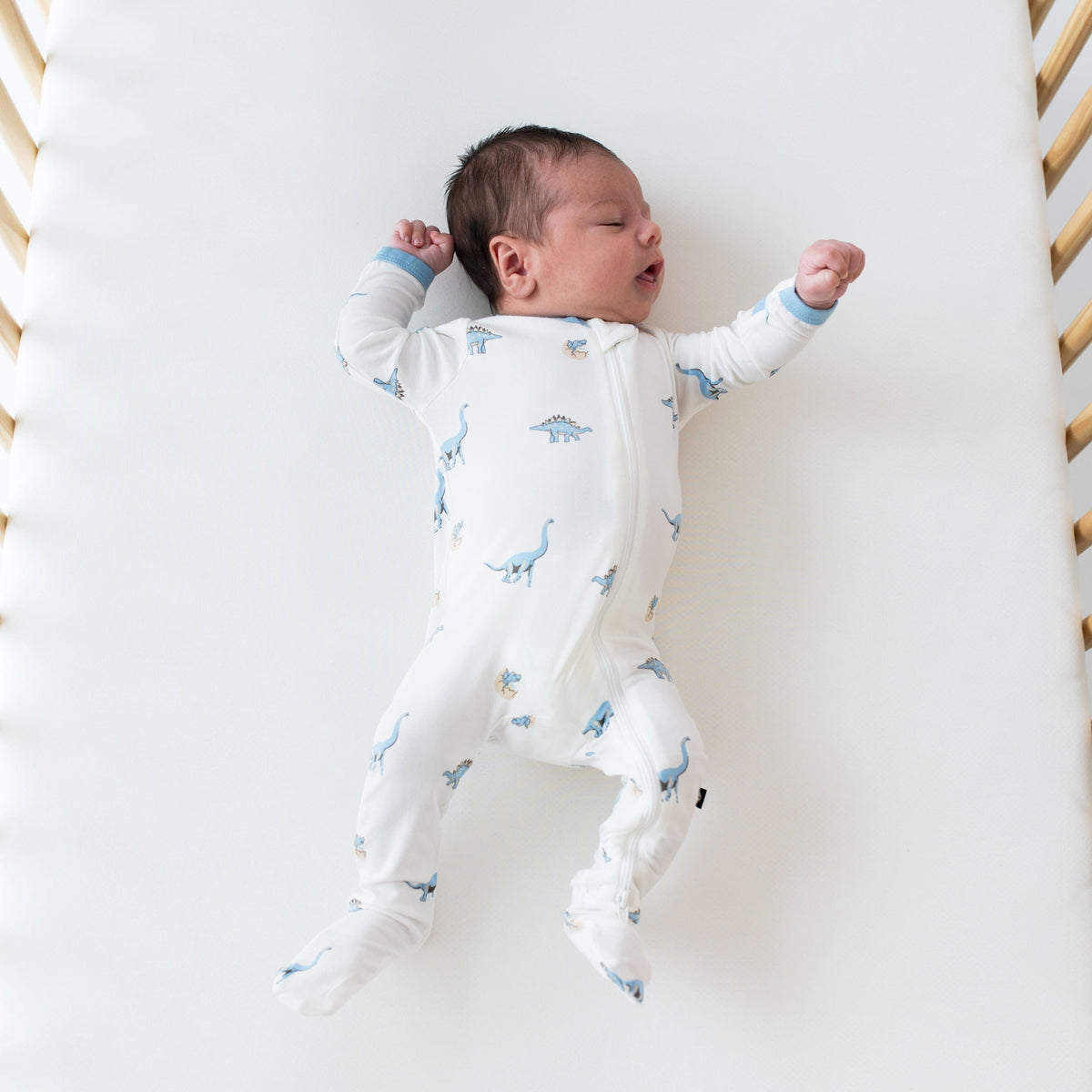 Newborn wearing Kyte Baby Zippered Footie in Jurassic