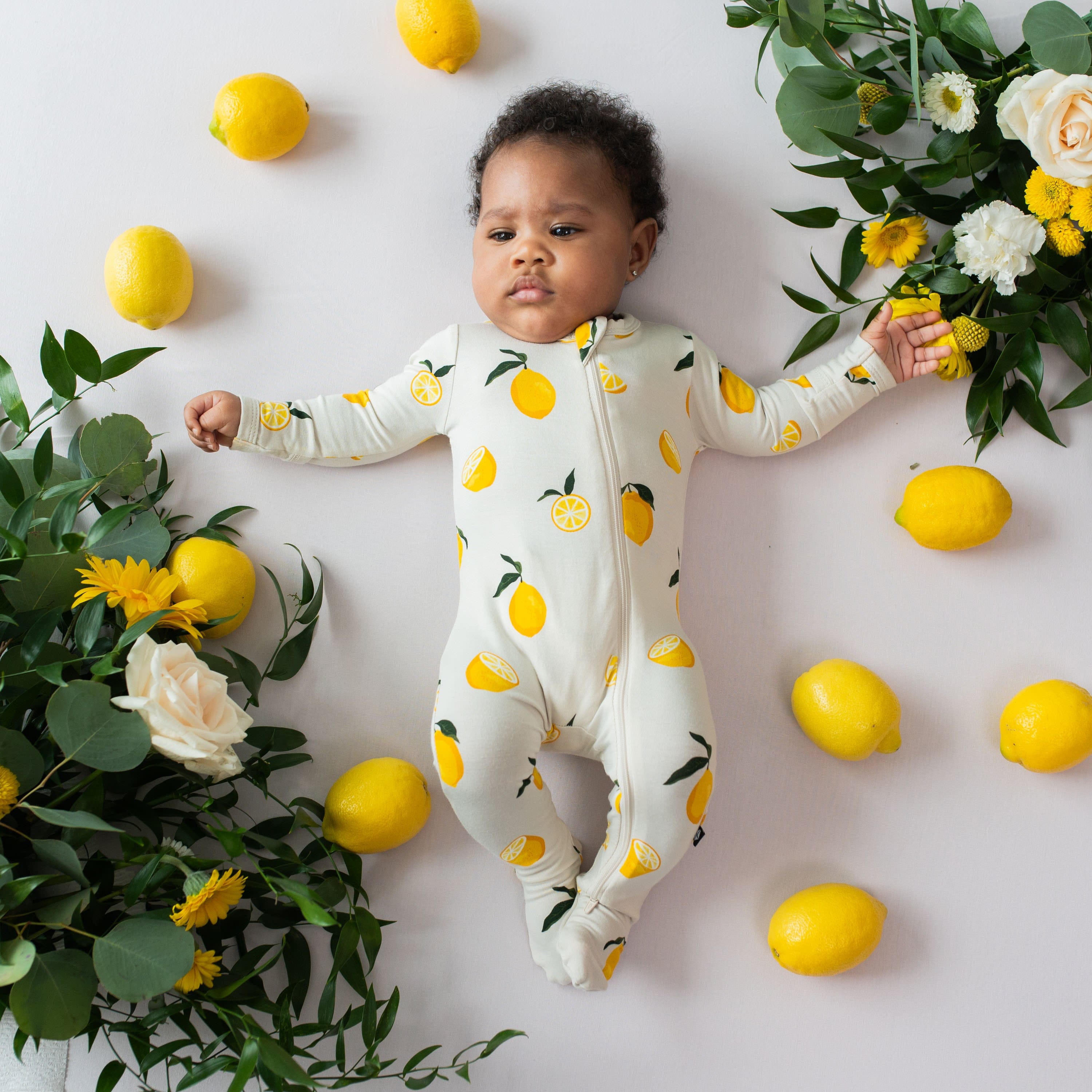 Infant wearing the Zippered Footie bamboo pajamas in Lemon print