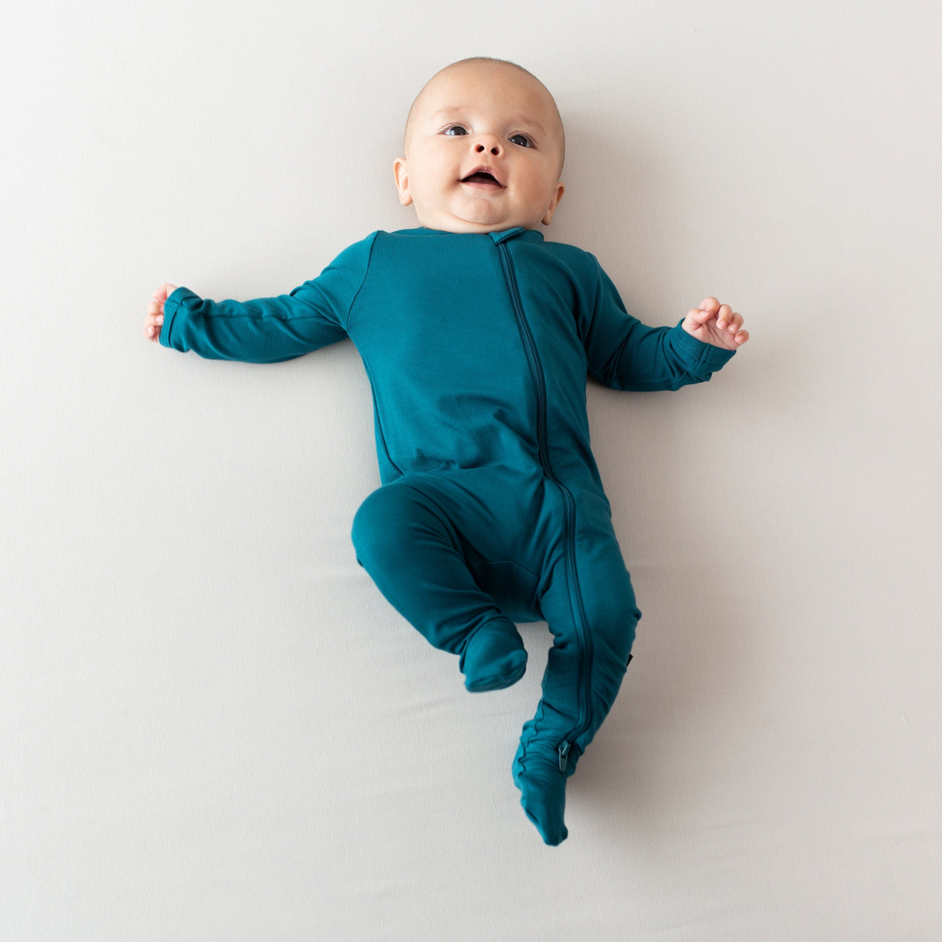 Baby wearing the Zippered Footie in Loch dark blue