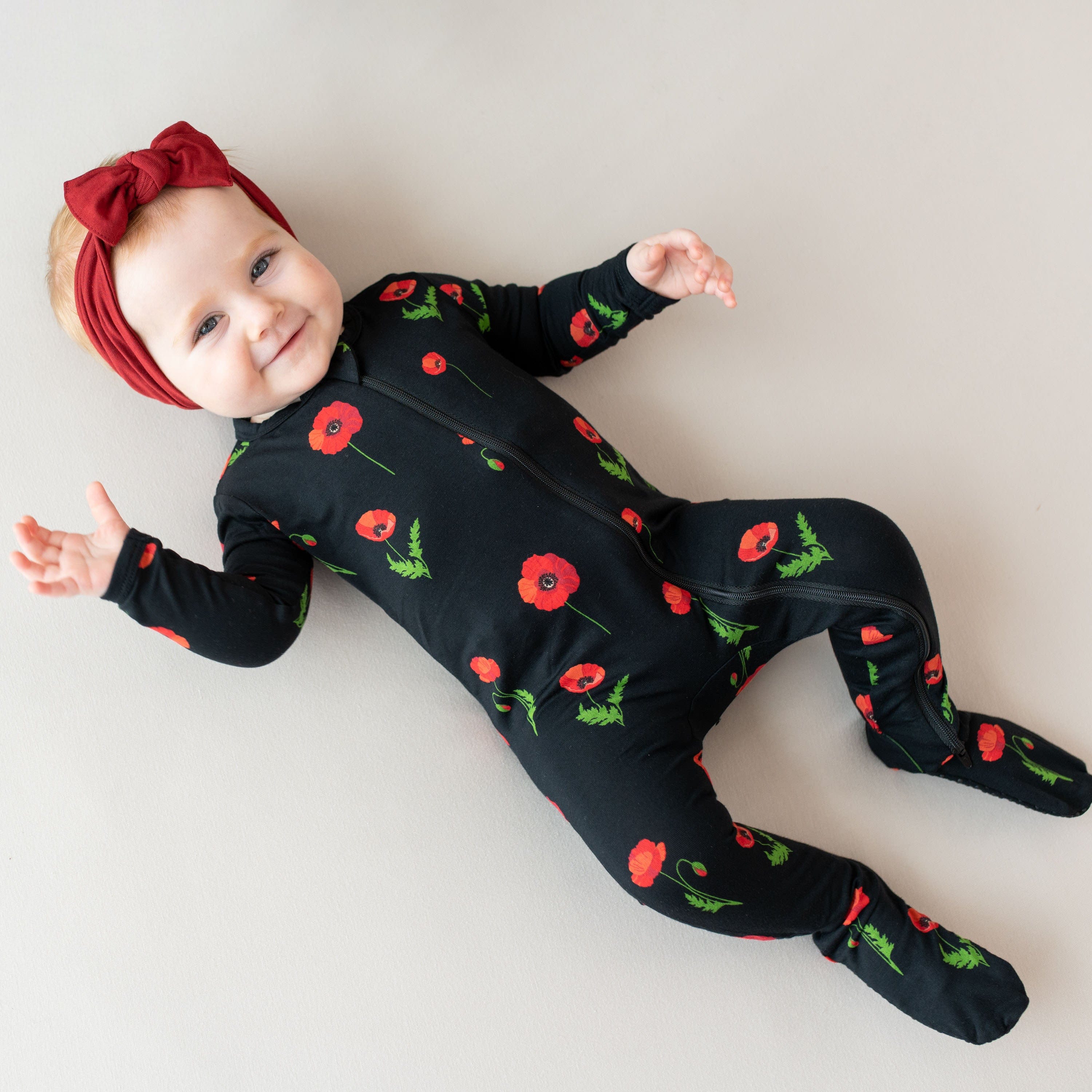 Infant wearing Kyte Baby Zippered Footie in Midnight Poppies