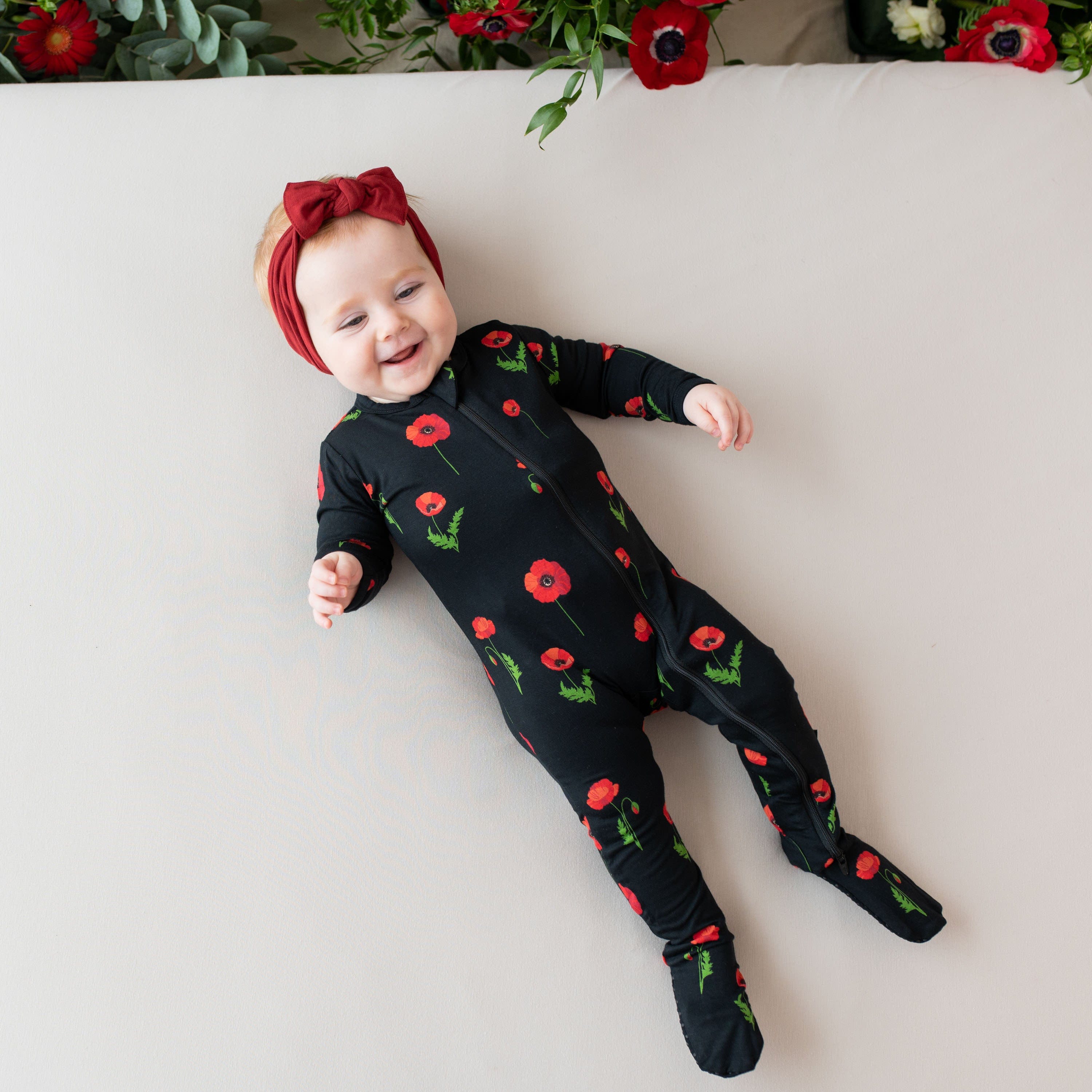 Infant wearing Kyte Baby breathable bamboo Zippered Footie in Midnight Poppies