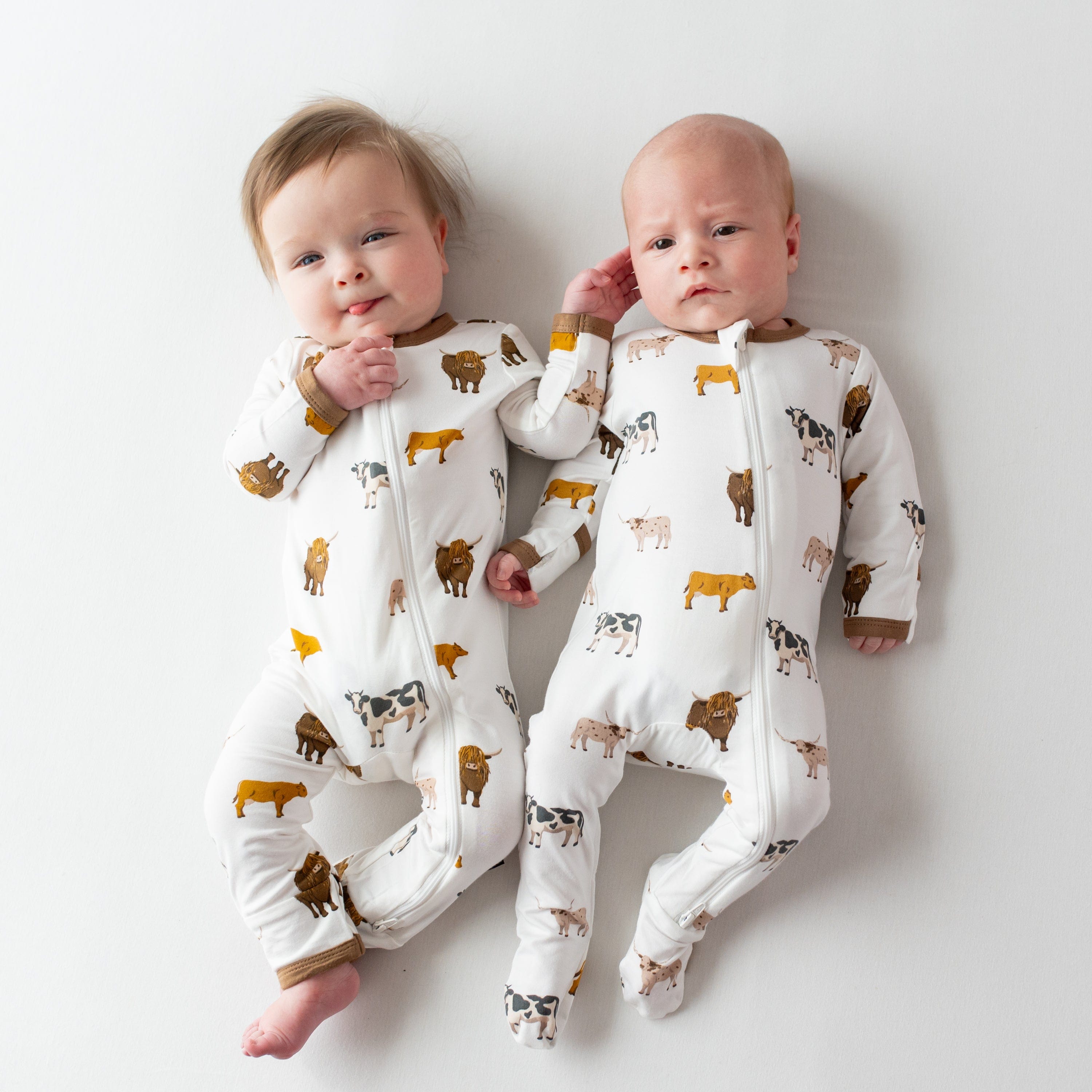 Babies wearing Kyte Baby matching zippered pajamas in Moo cow print