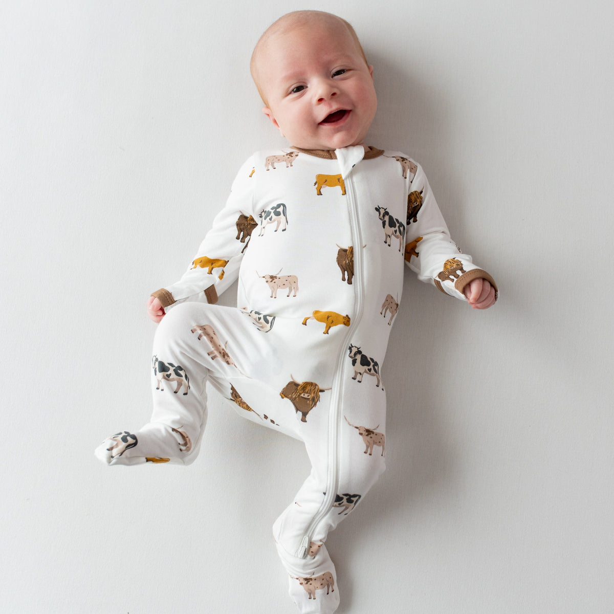 Infant wearing Kyte Baby Zippered Footie in Moo