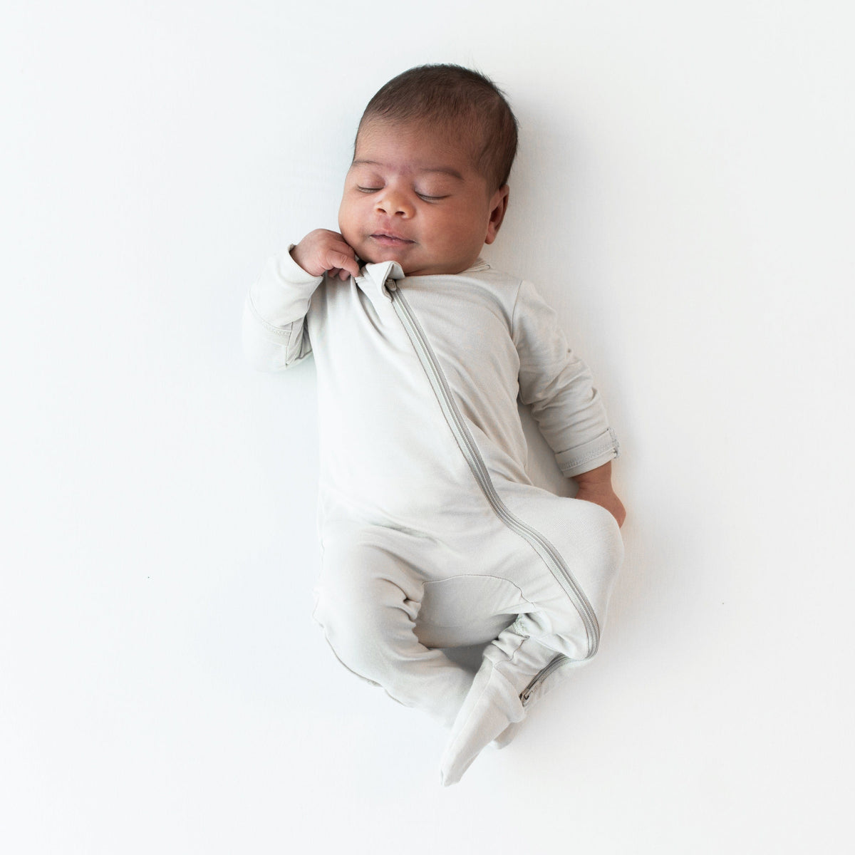 Sleeping infant wearing the Zippered Footie in Oat