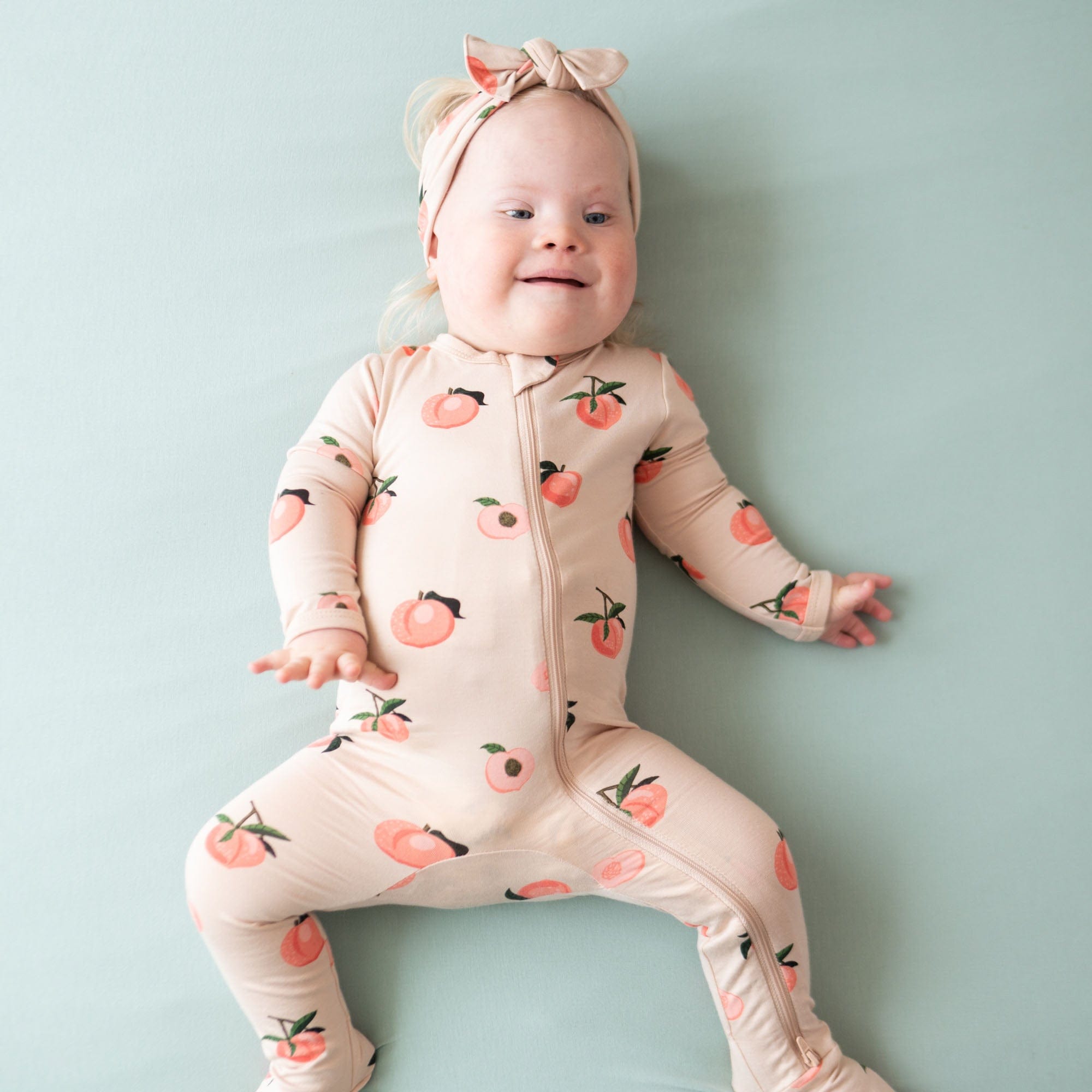 Infant wearing Kyte Baby Zippered Footie in Peach