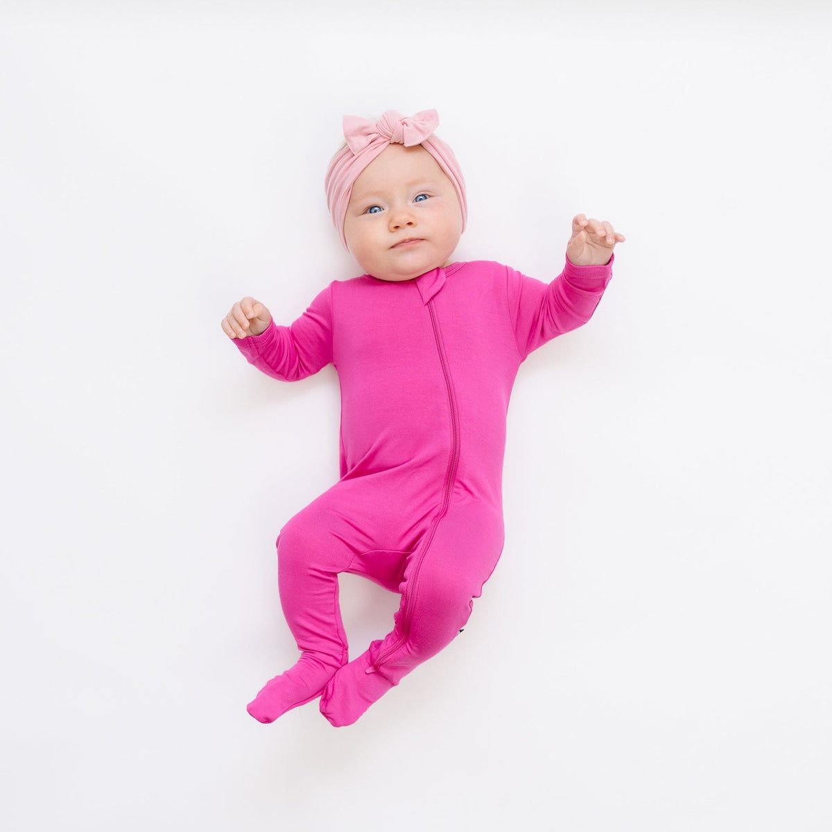 Infant wearing Kyte Baby Zippered Footie in Raspberry