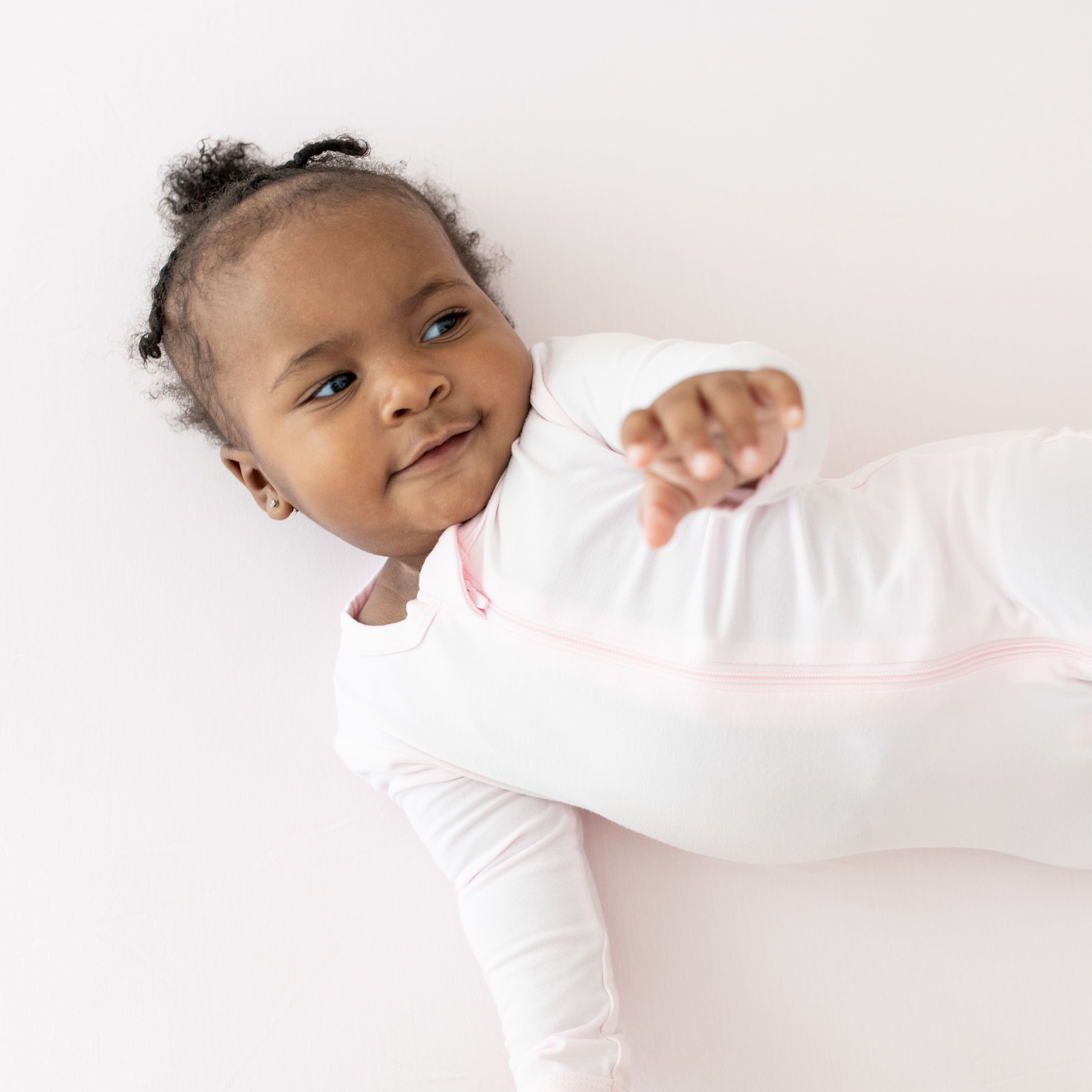 Infant wearing Kyte Baby Zippered Footie in Sakura