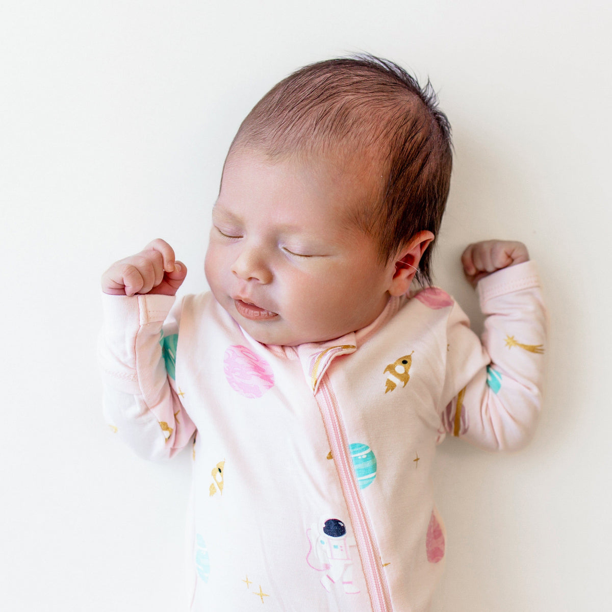 Sleeping infant wearing the Zippered Footie in Sakura Space