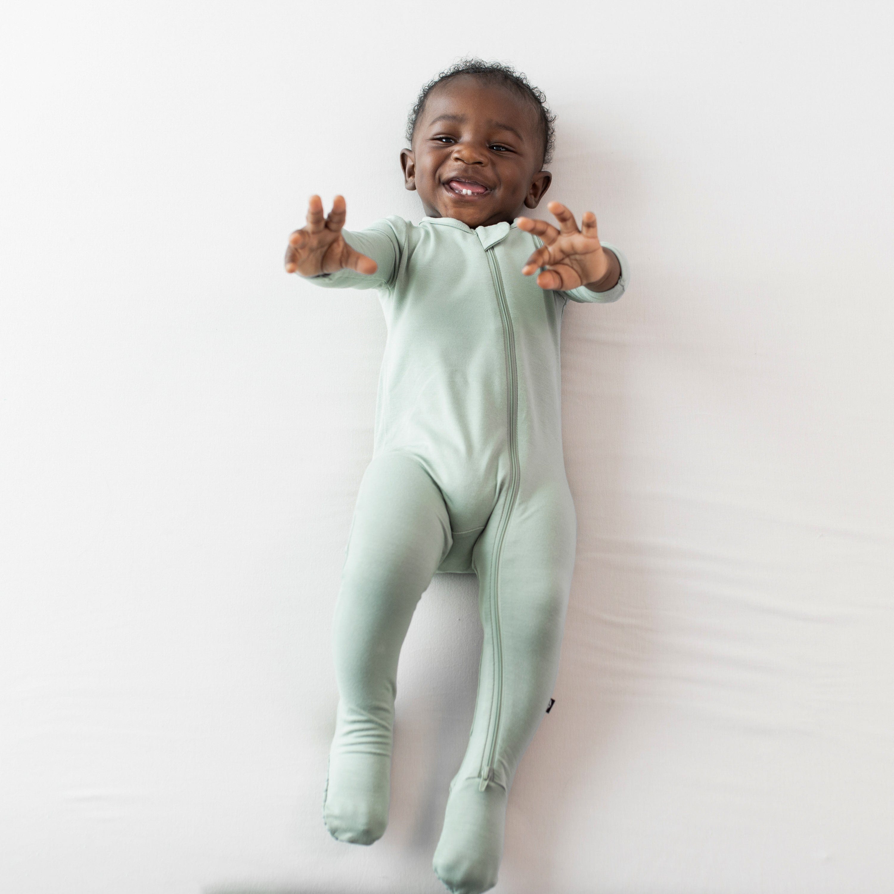 Infant wearing Zippered Footie bamboo pajamas in Thyme green