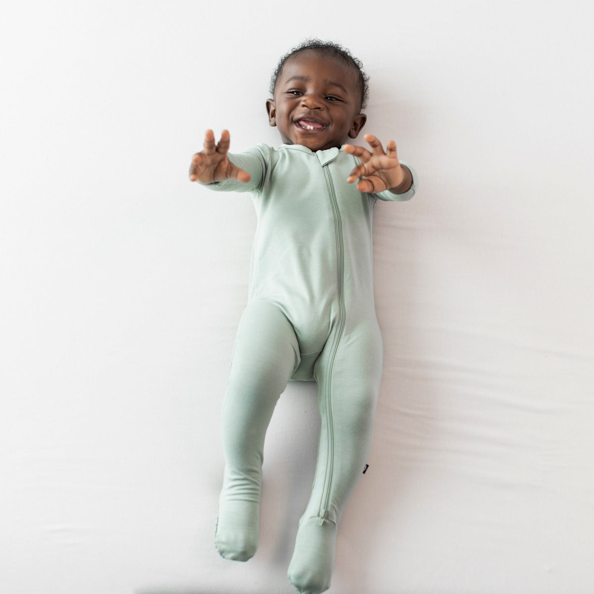 Infant wearing Zippered Footie bamboo pajamas in Thyme green