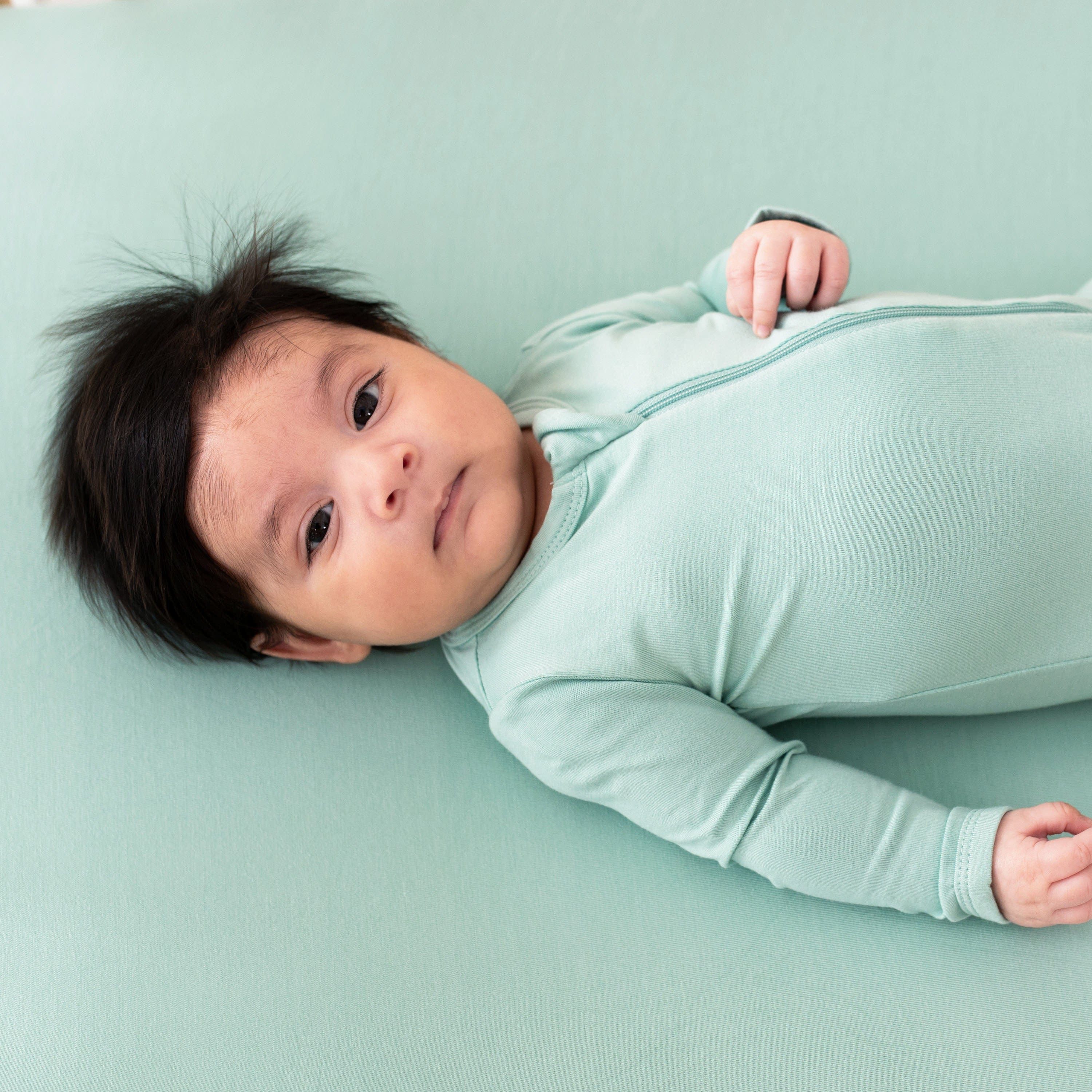 Infant wearing Kyte Baby Zippered Footie pajamas in Wasabi green