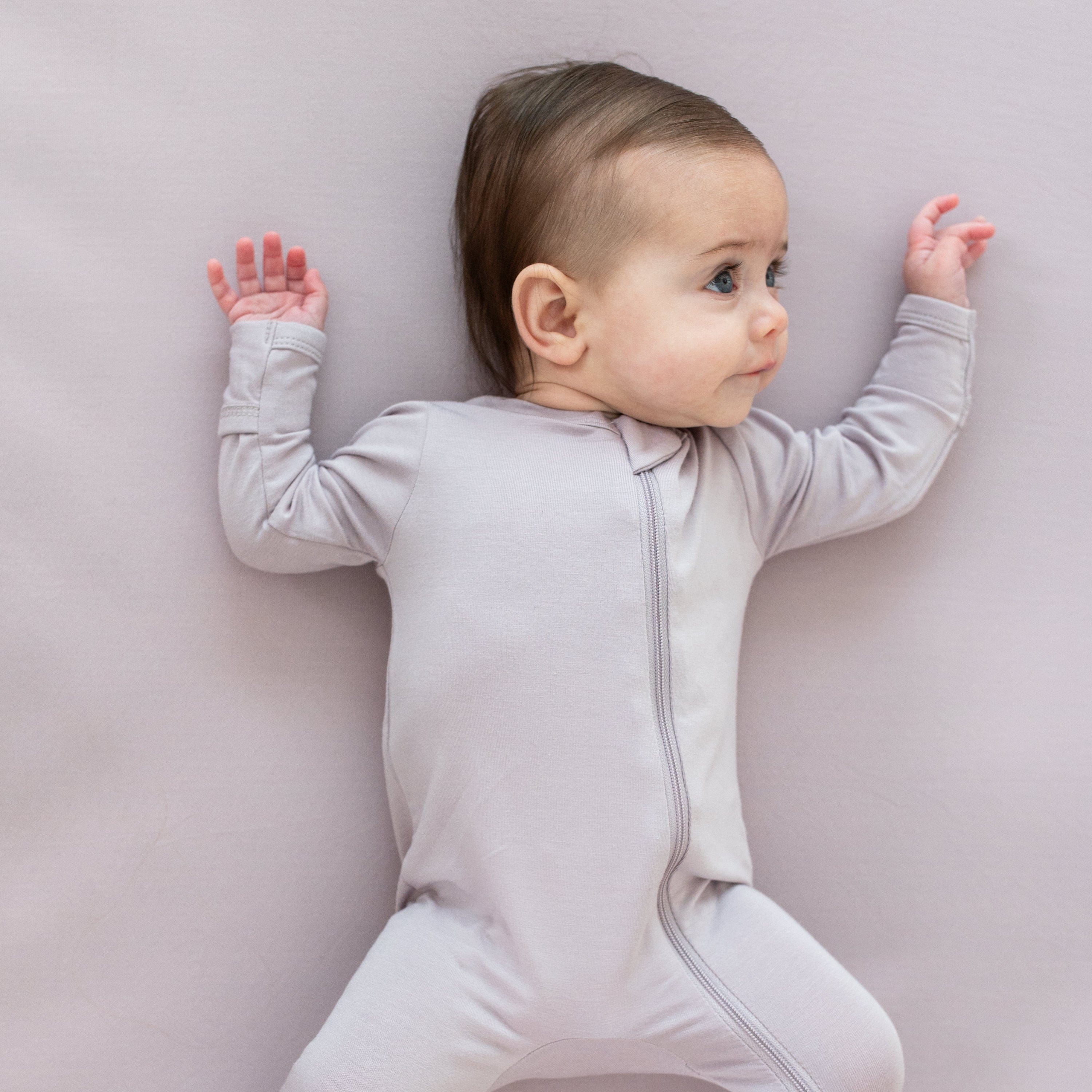 Infant wearing Kyte Baby Zippered Footie pajamas in Wisteria purple